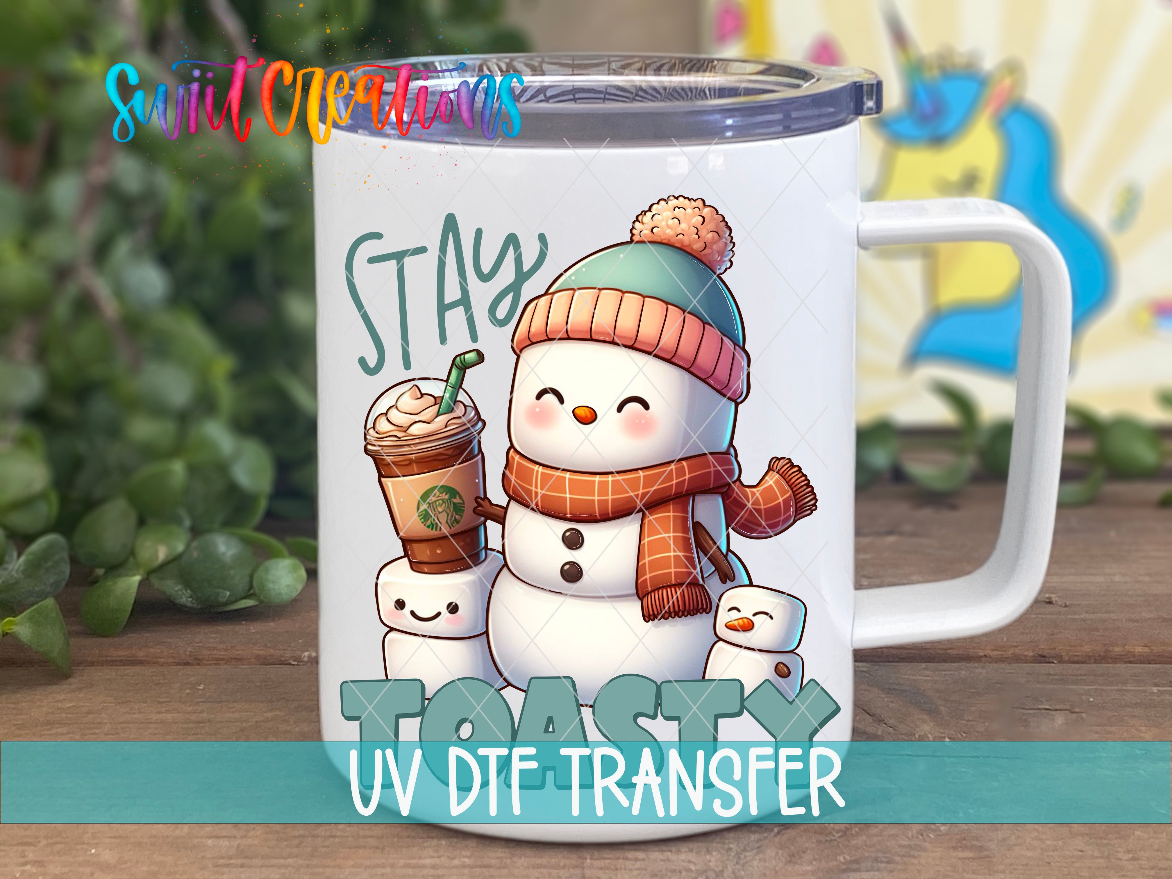 A mug with a snowman and marshmallow design, along with the text "STAY TOASTY UV DTE TRANSFER".