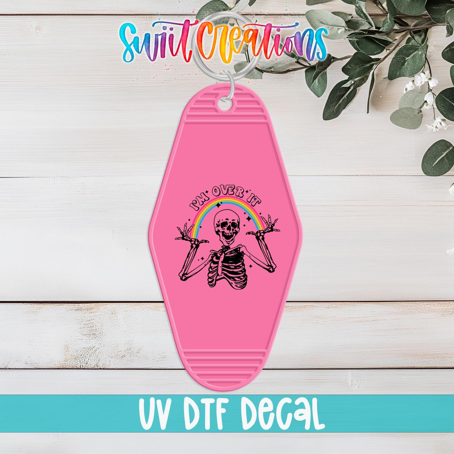 A pink keychain with a skeleton and rainbow graphic, along with the text "Swit Creations UV Dtf Decal".