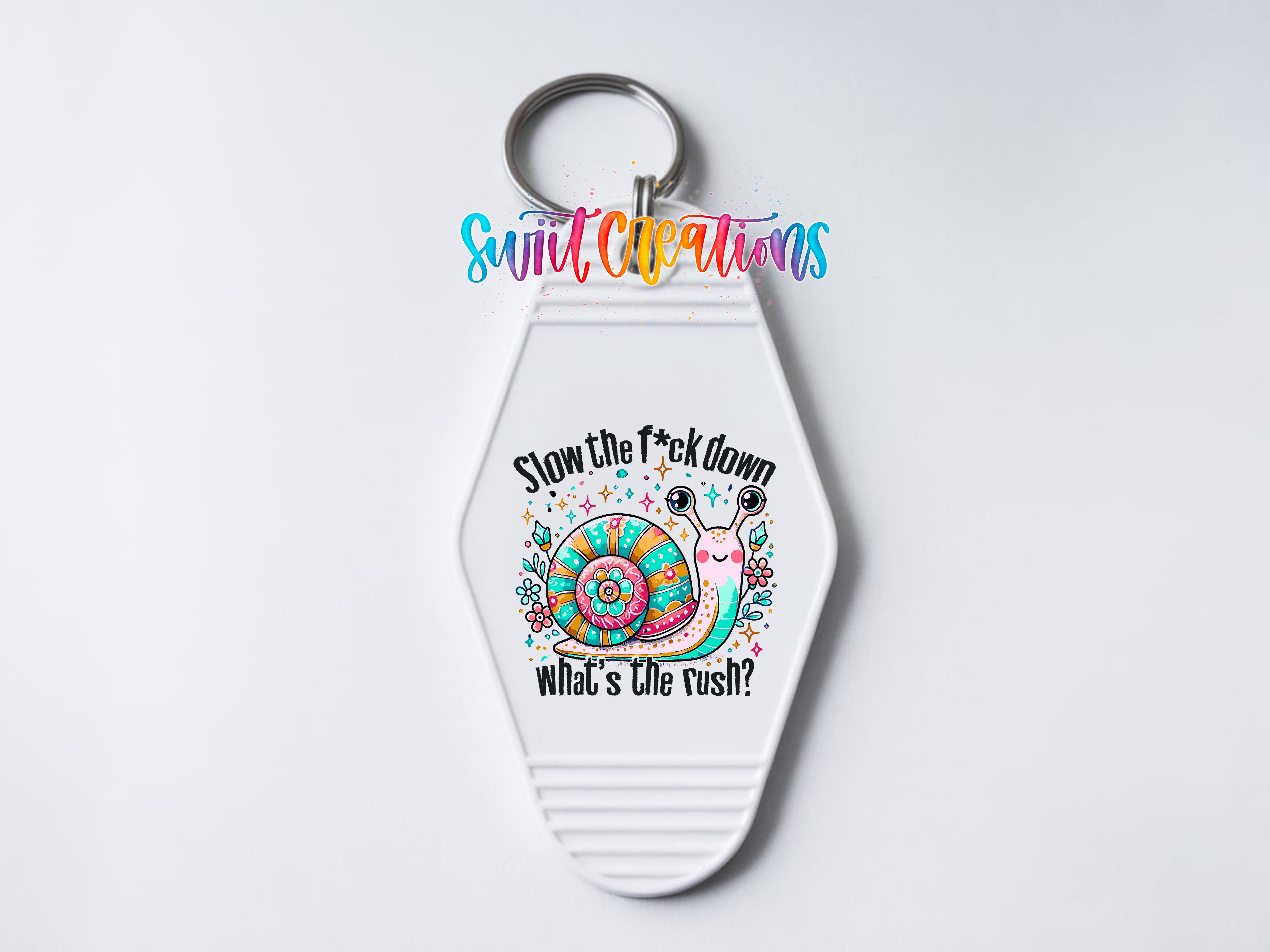 A keychain with a colorful snail design and text that says "Slow the fuck down what's the rush?".