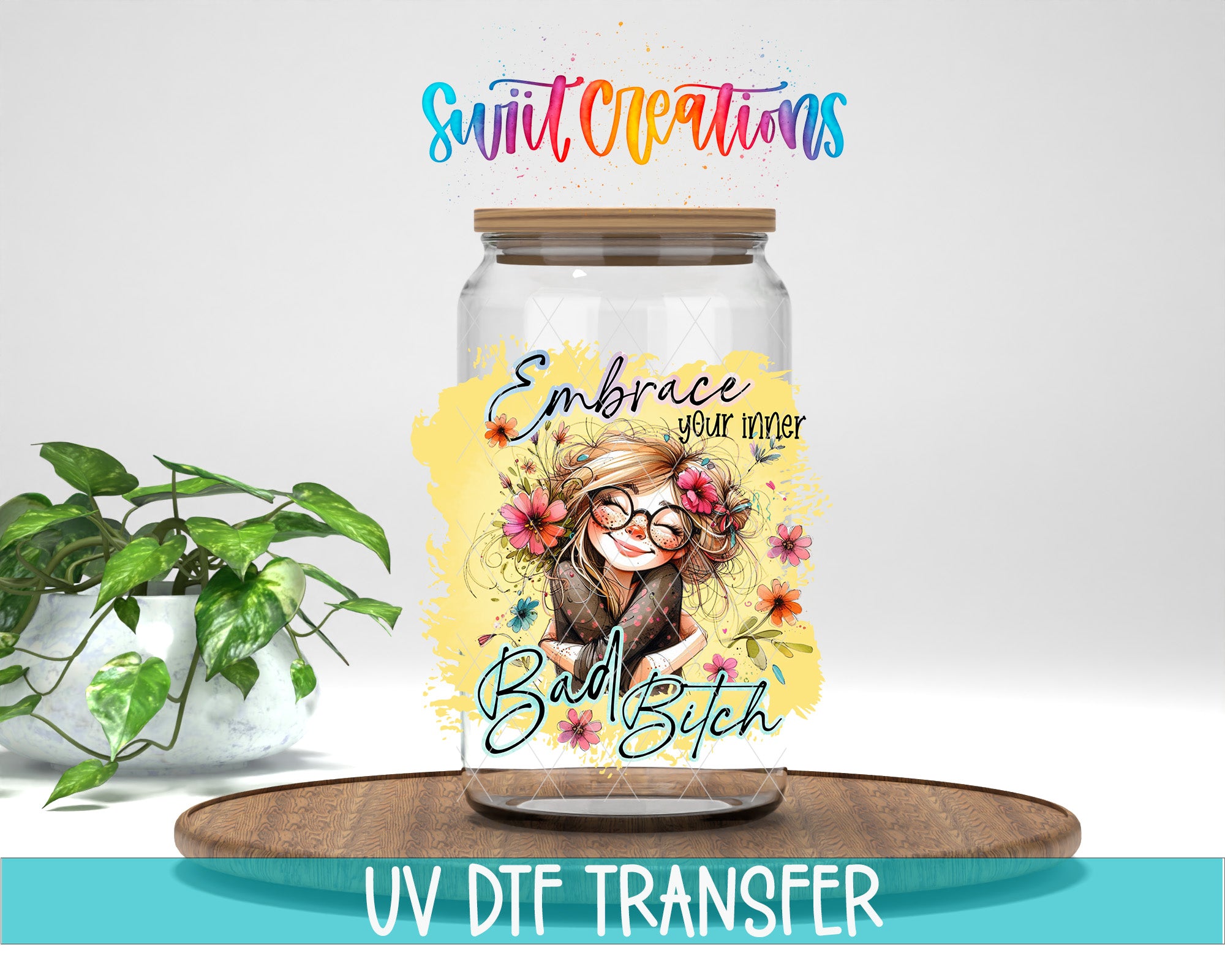 a glass jar with a colorful design and text, placed on a wooden surface next to a potted plant.