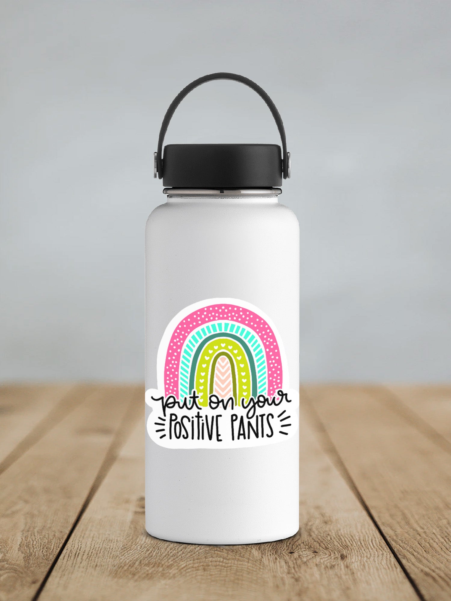 a white insulated water bottle with a black lid on a wooden table