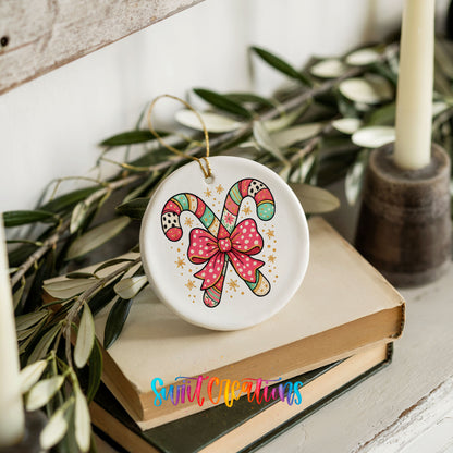 A white ceramic ornament with a colorful candy cane design and a pink bow sits on top of a stack of books.
