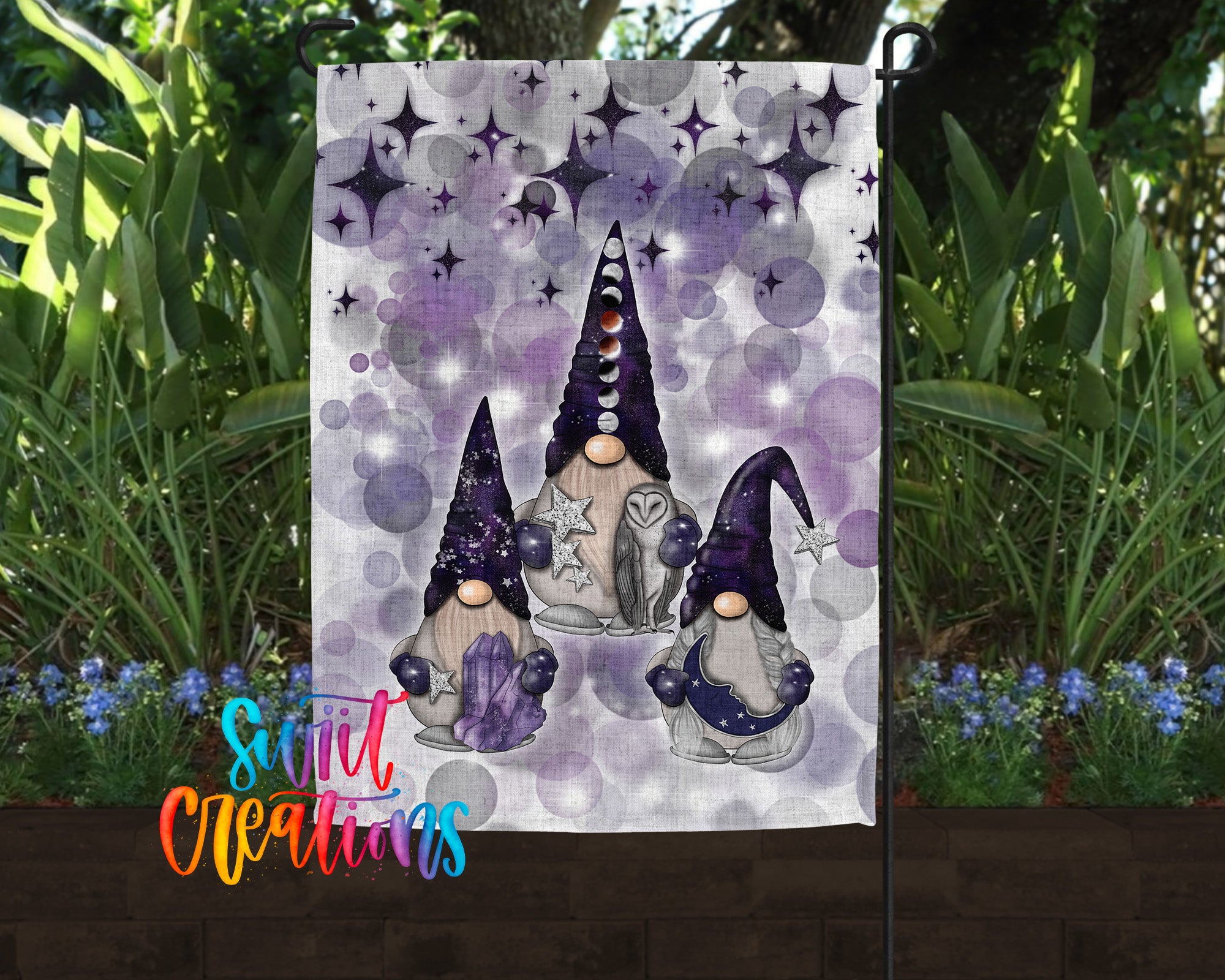A garden flag featuring three gnomes with purple hats and star-patterned hair, set against a backdrop of purple and white stars and plants.