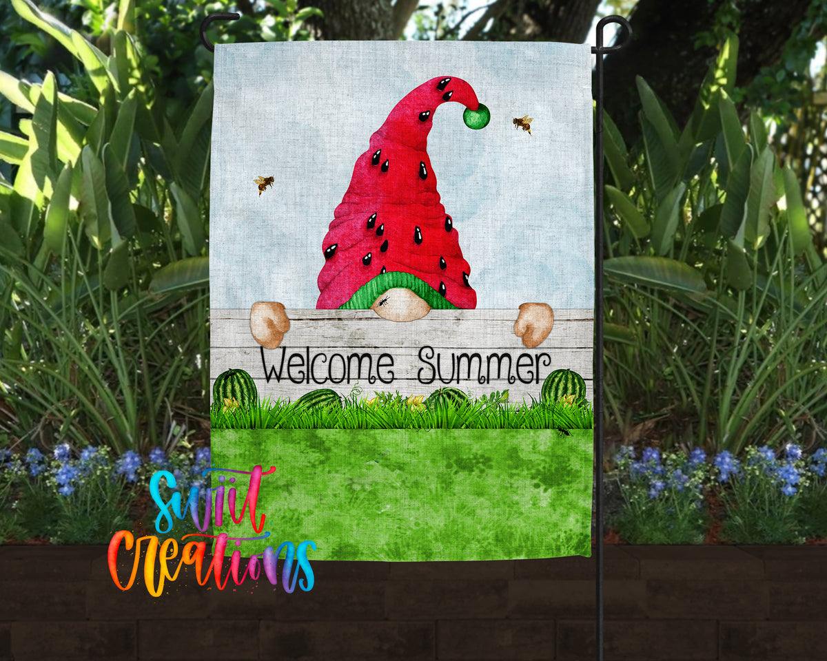 A garden flag featuring a gnome wearing a red hat with a watermelon design, standing behind a wooden fence with the text "Welcome Summer" displayed on it.