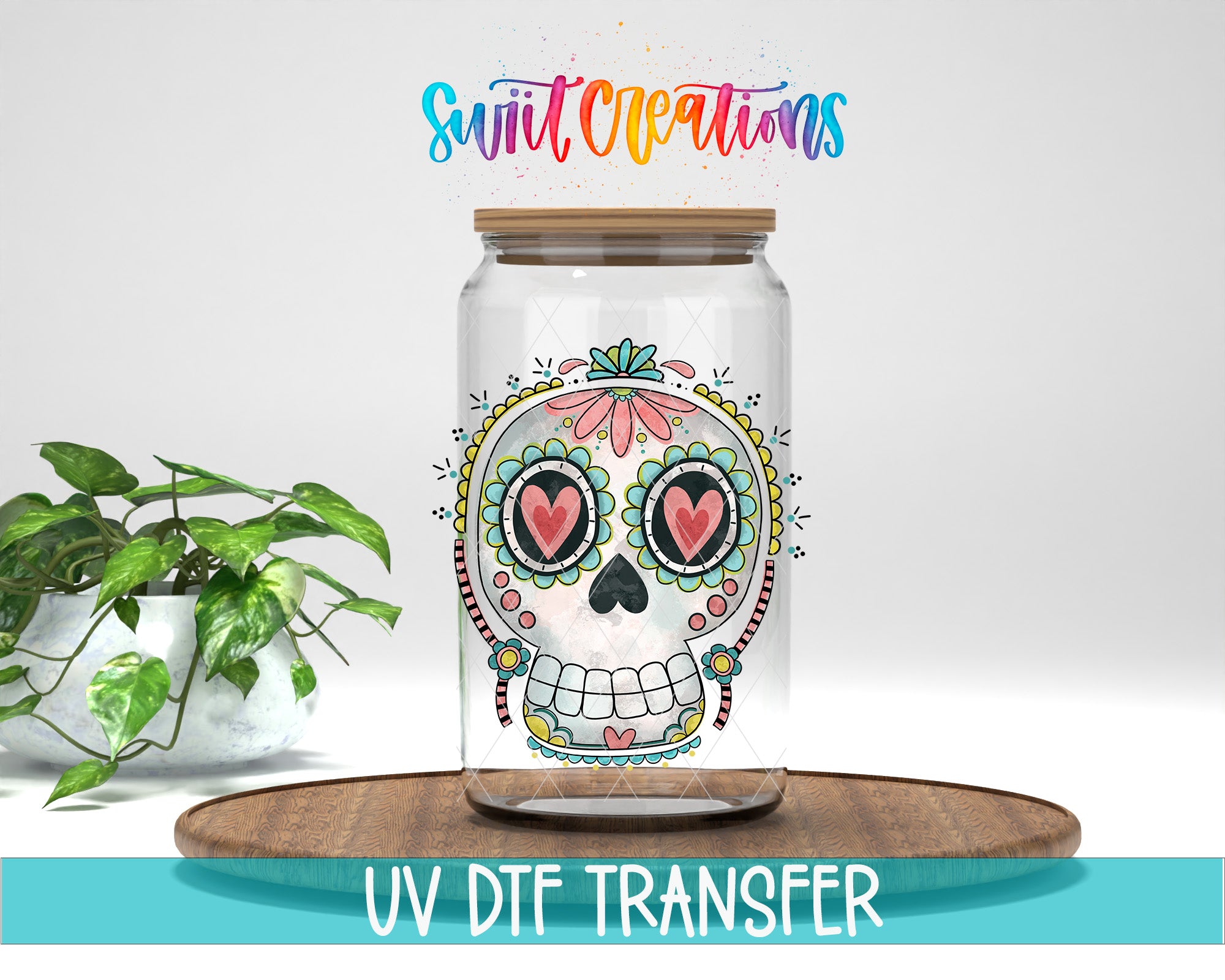 A glass jar with a colorful sugar skull design on it, placed on a wooden surface. There is a potted plant in the background.