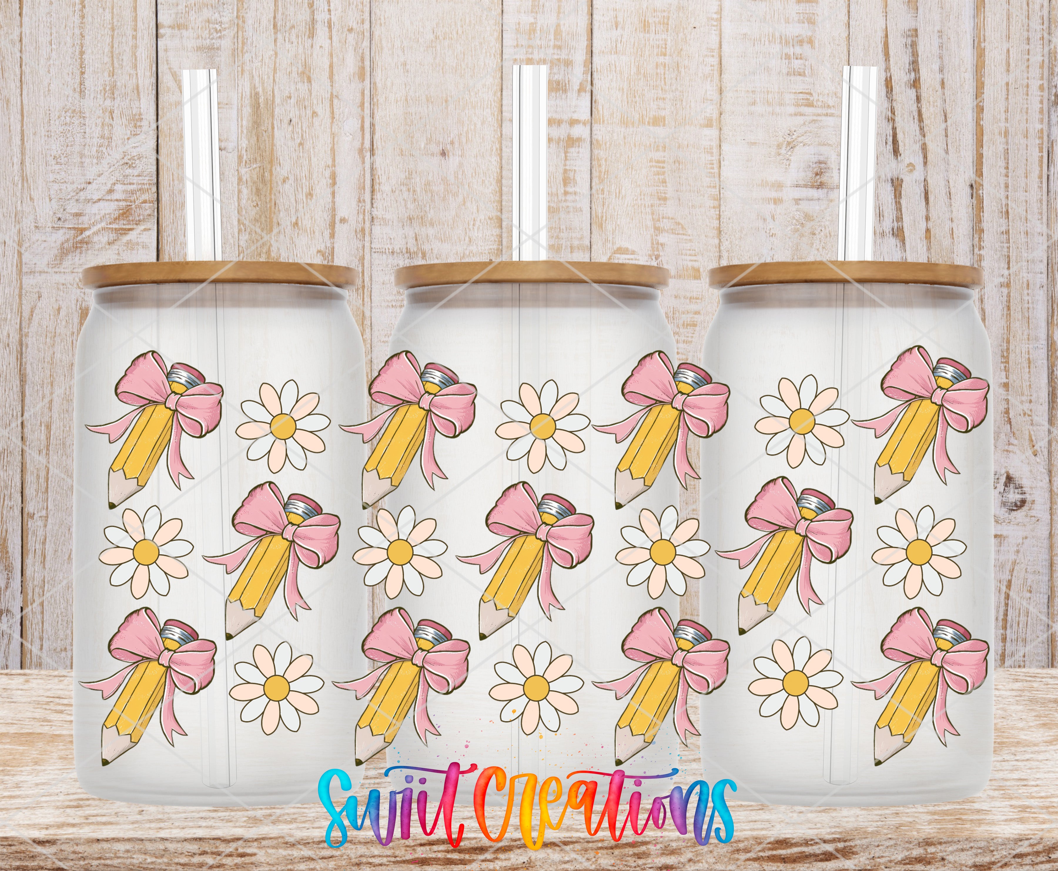 Three glass tumblers with a bow and flower design on them, placed on a wooden surface.