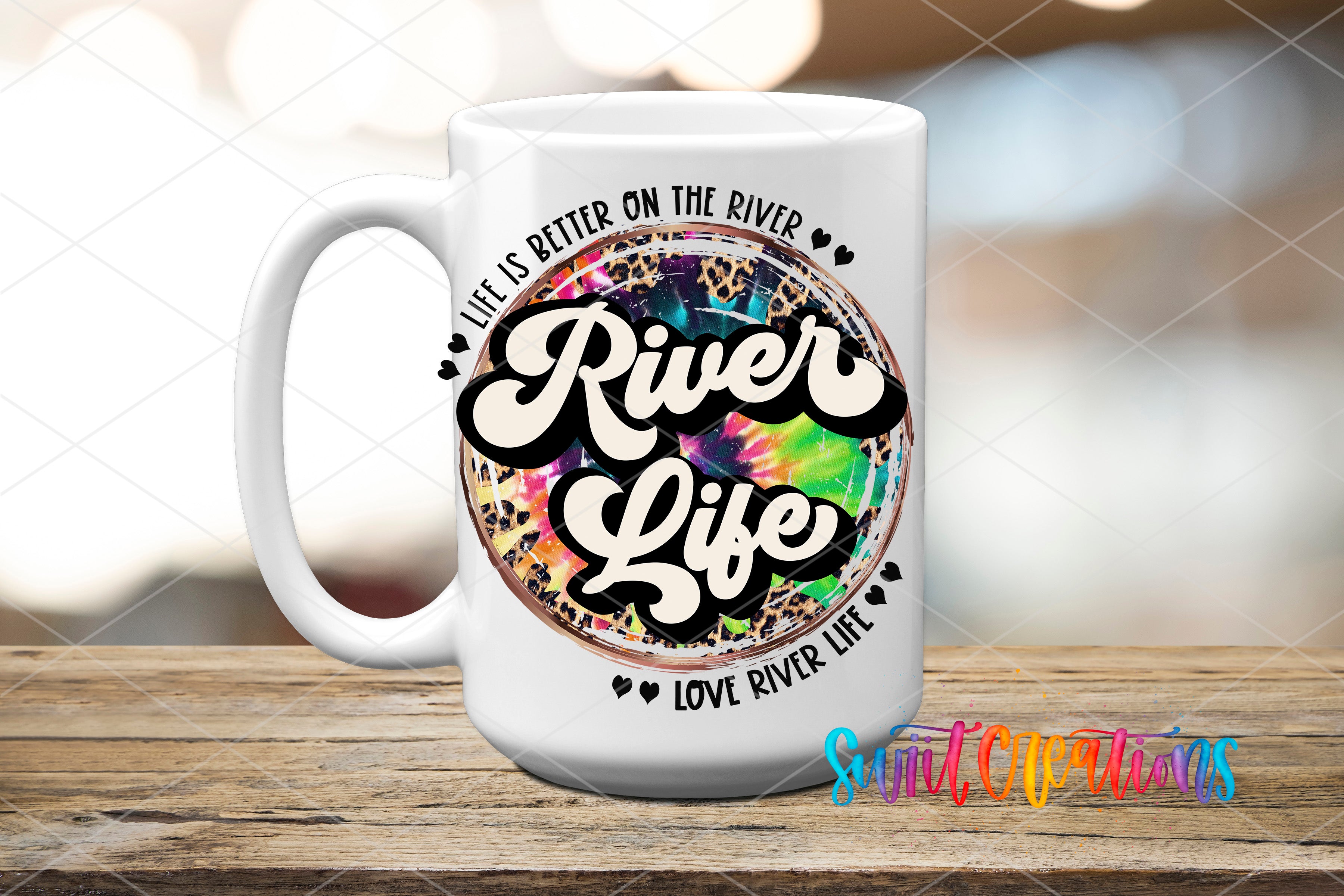A white ceramic mug with a colorful, tie-dye design and text printed on it, placed on a wooden surface.