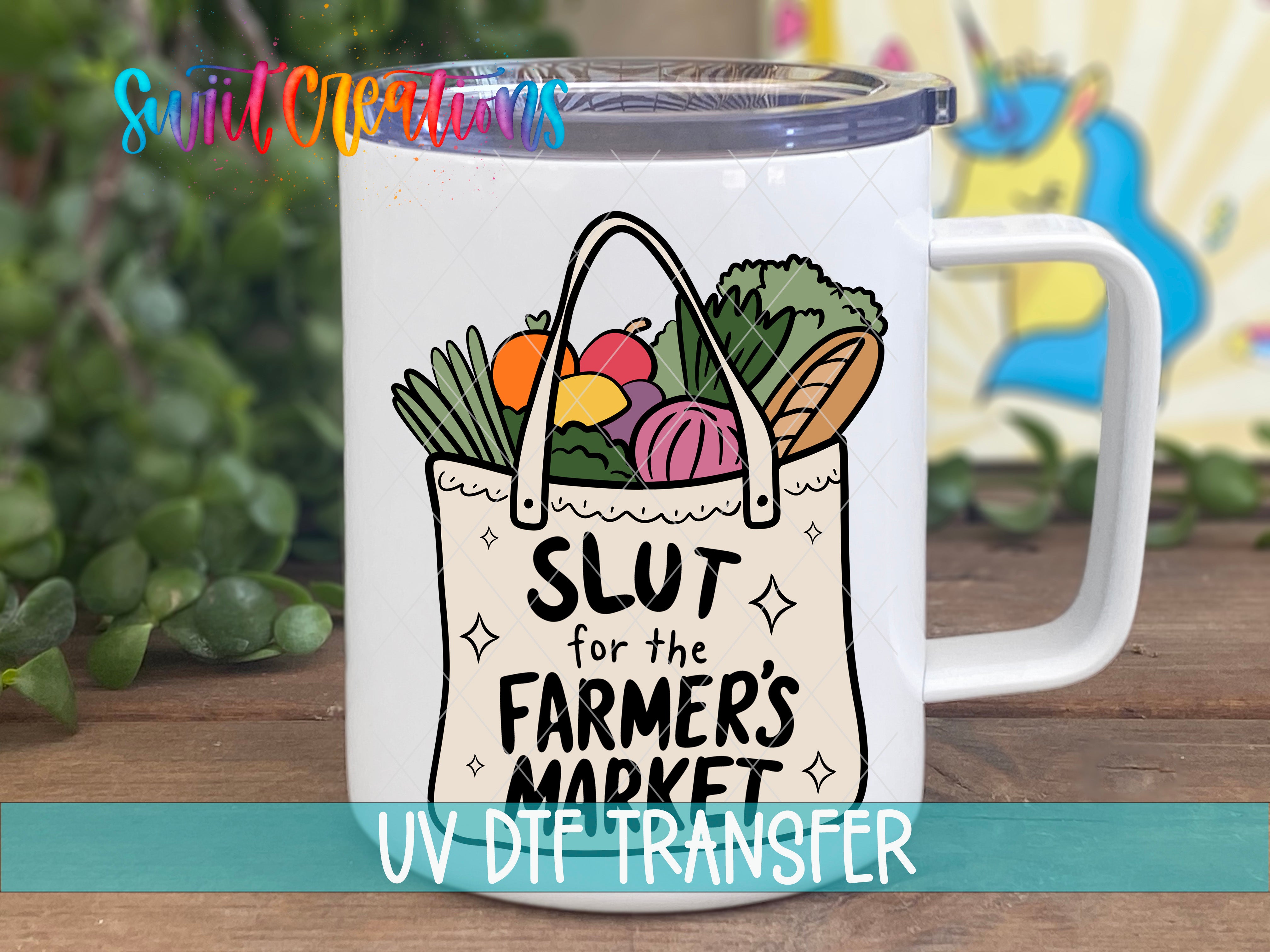 A white mug with a printed design on it, featuring a bag with various fruits and vegetables, along with the text "SLUT for the FARMER'S MARKET" printed on it.