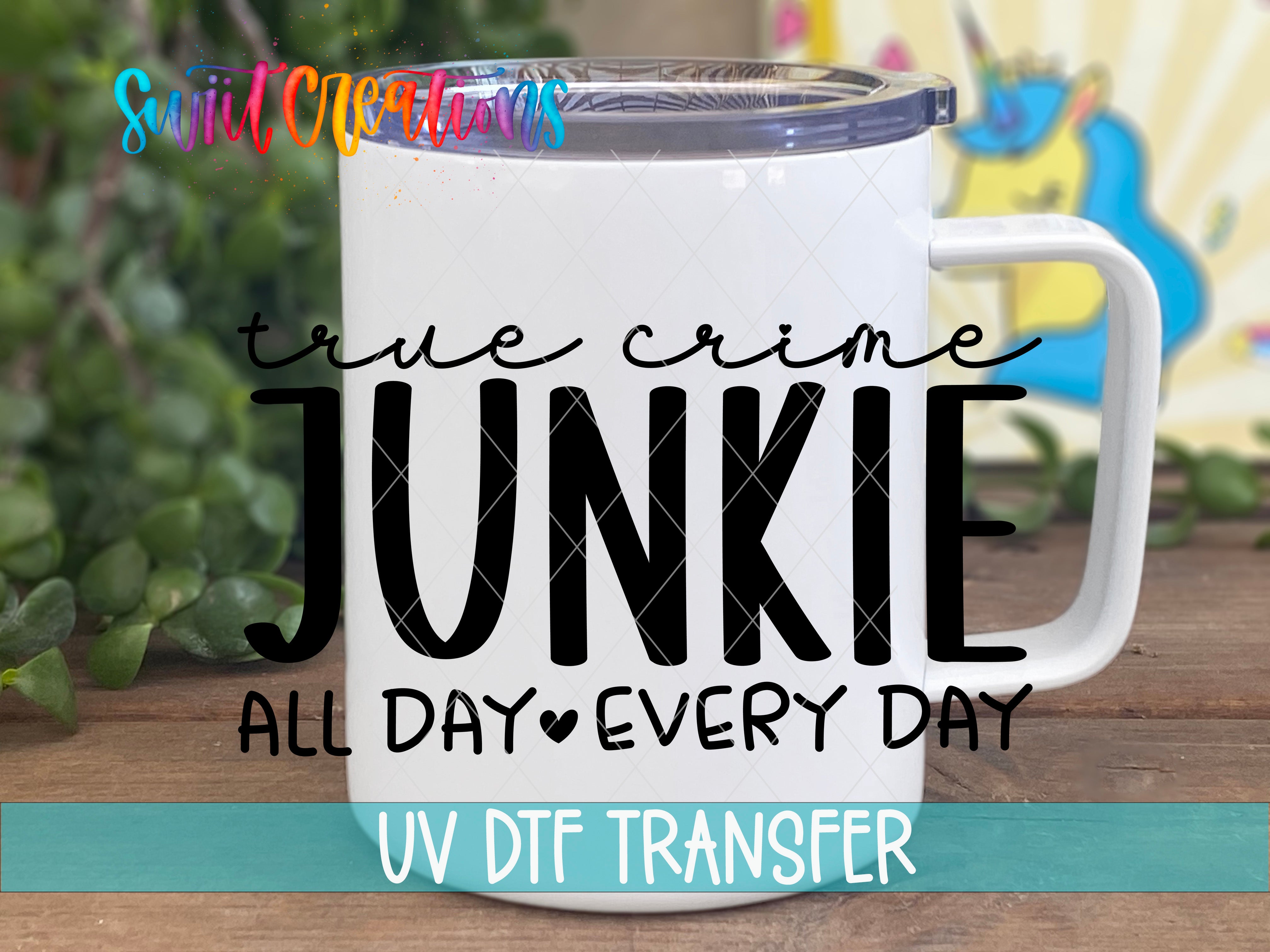 A white mug with a printed text design on it, placed on a wooden surface with a colorful background.