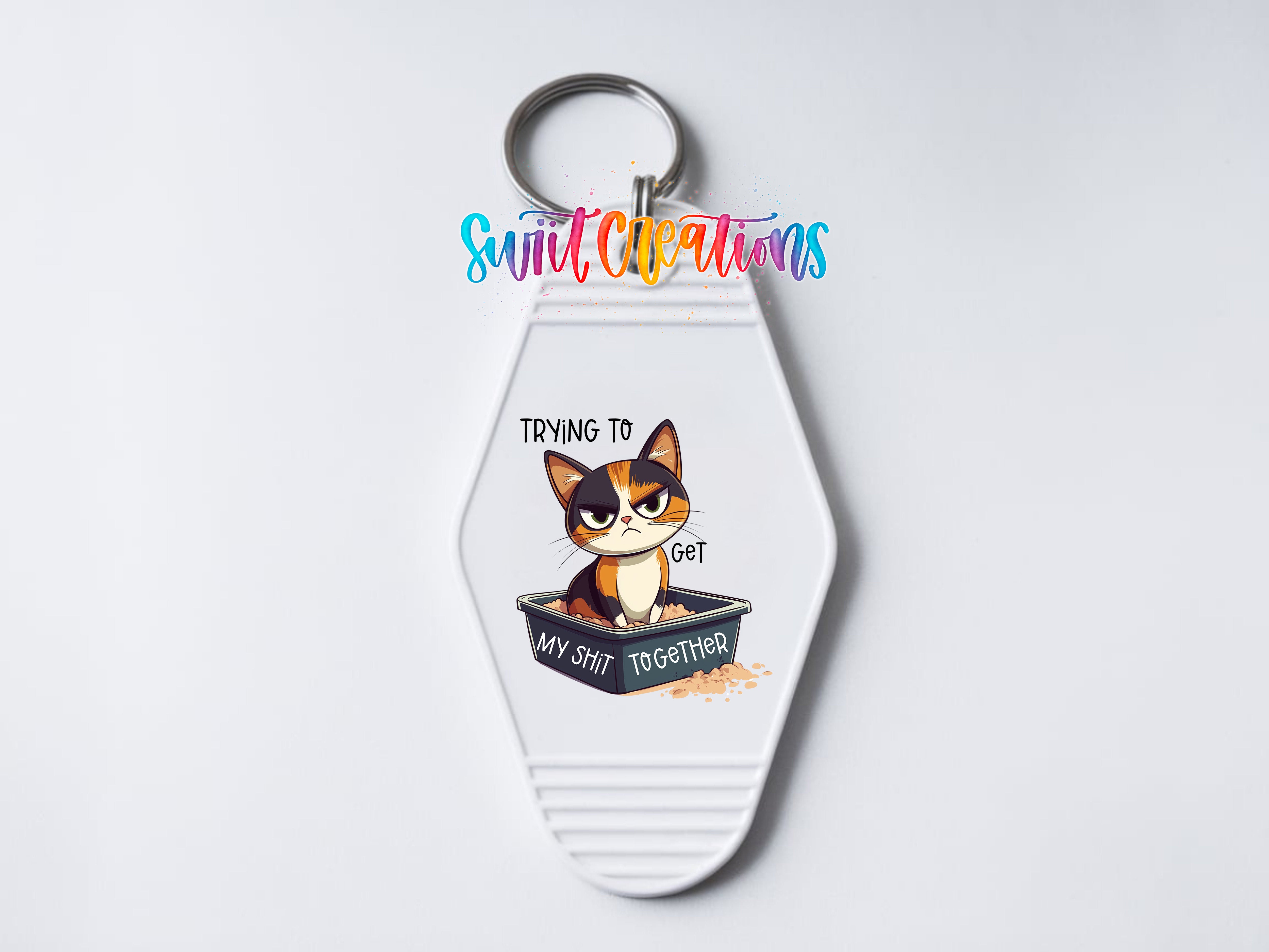 A keychain with a cartoon cat and the text "Trying to get my shit together" printed on it.