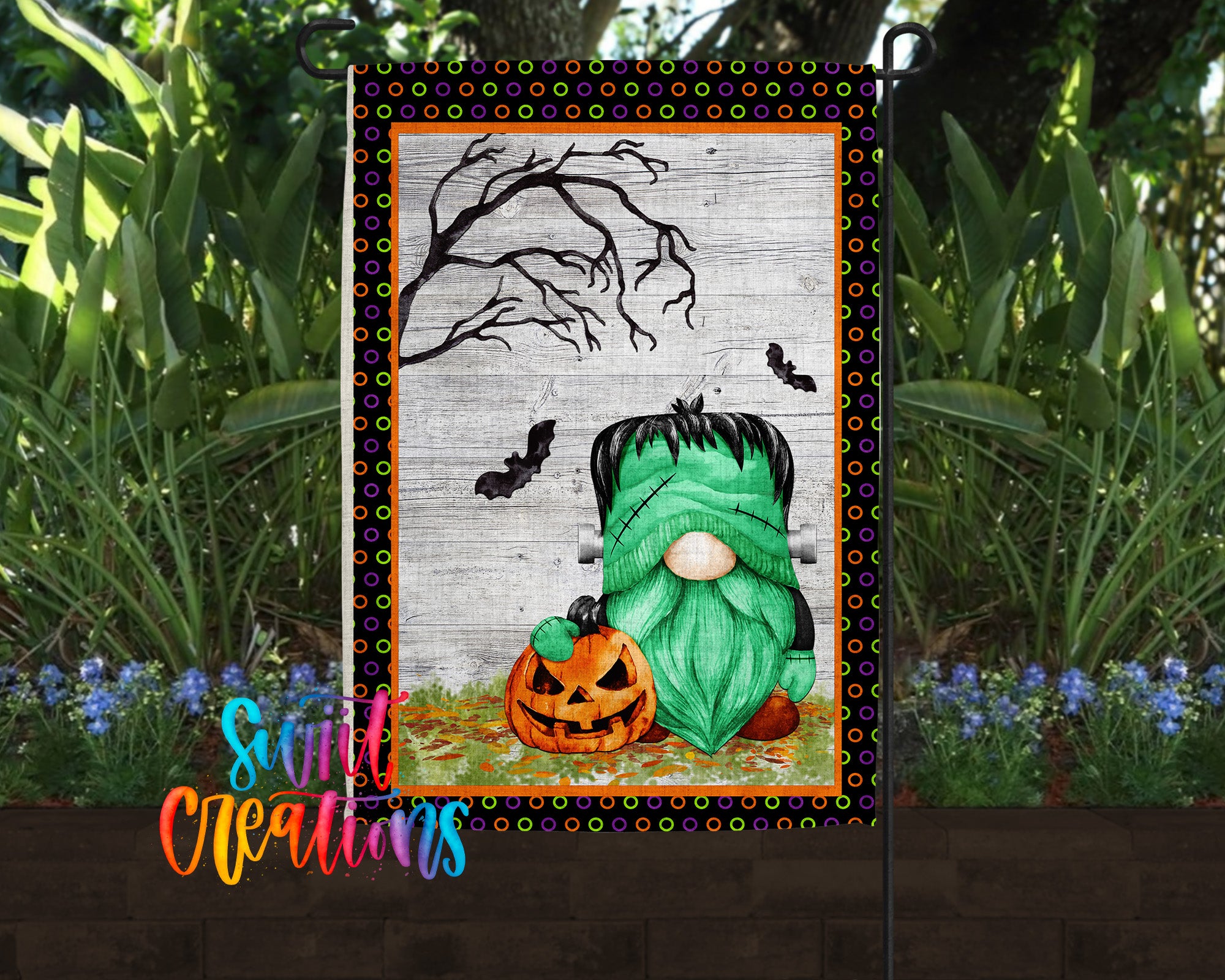 A Halloween-themed garden flag featuring a green gnome holding a carved pumpkin, with a spooky tree and bats in the background.