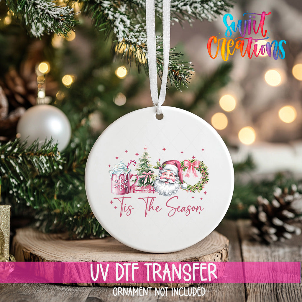 A white ceramic ornament with a Santa Claus and Christmas tree design hangs on a Christmas tree.