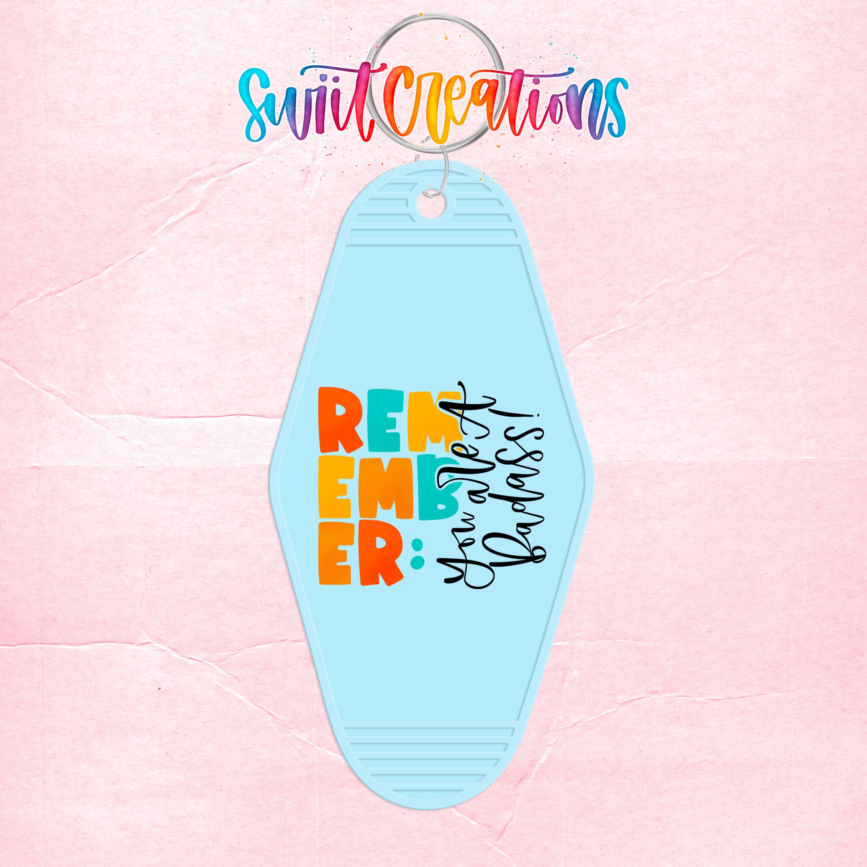 A keychain with the text "Remember" and "You're a badass" printed on it, along with a colorful design.