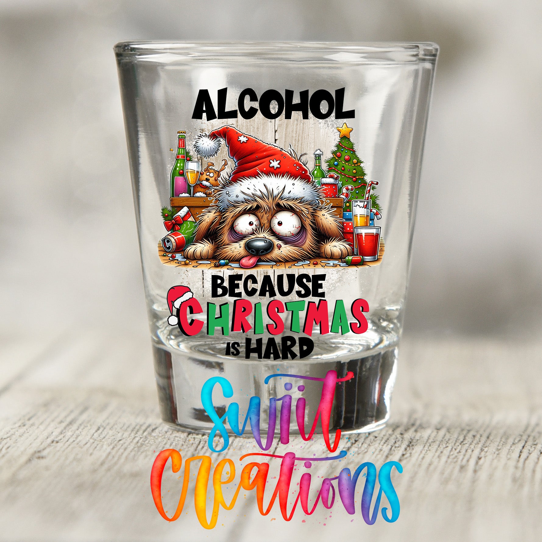 A glass shot glass with a Christmas-themed design and text, including a dog wearing a Santa hat and the text "ALCOHOL BECAUSE CHRISTMAS IS HARD" along with the phrase "Sweet Creations".