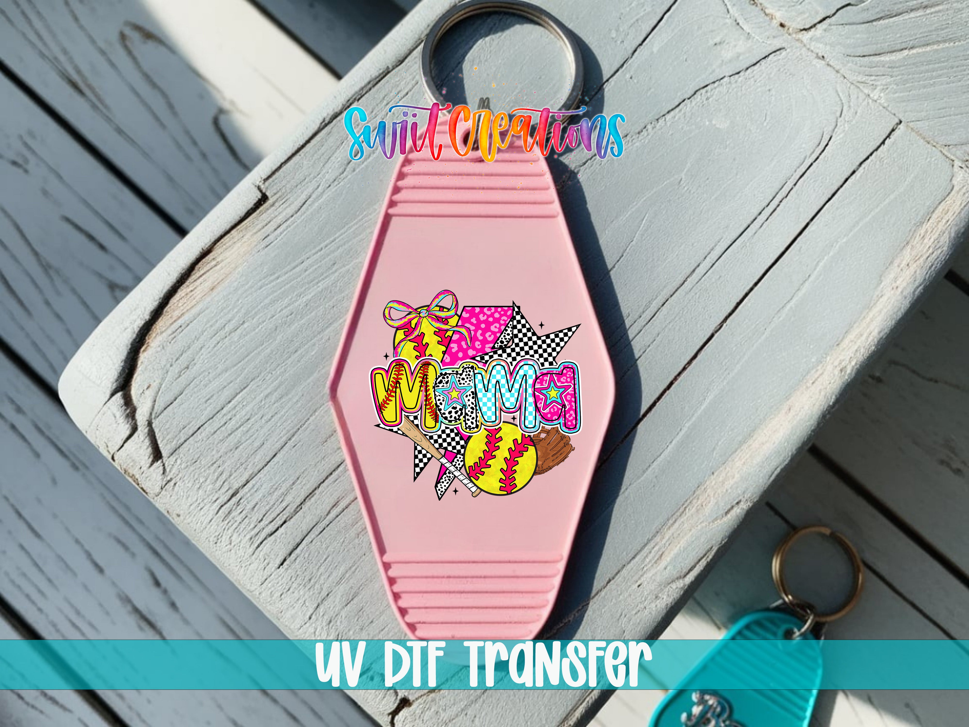A pink keychain with a colorful, retro-style design featuring a cartoon character and the word "MOMA" on it, placed on a wooden surface.