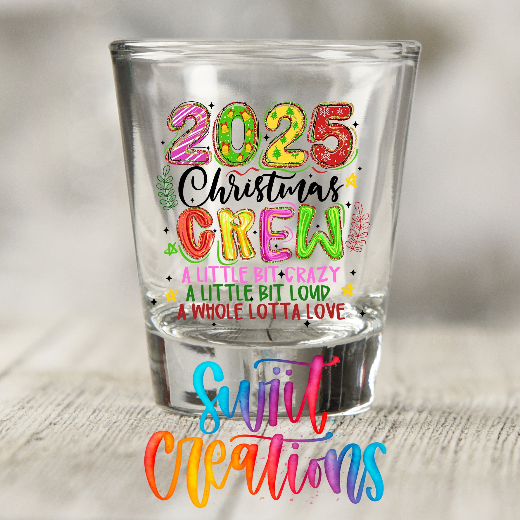 A shot glass with colorful text and graphics on it, placed on a wooden surface.