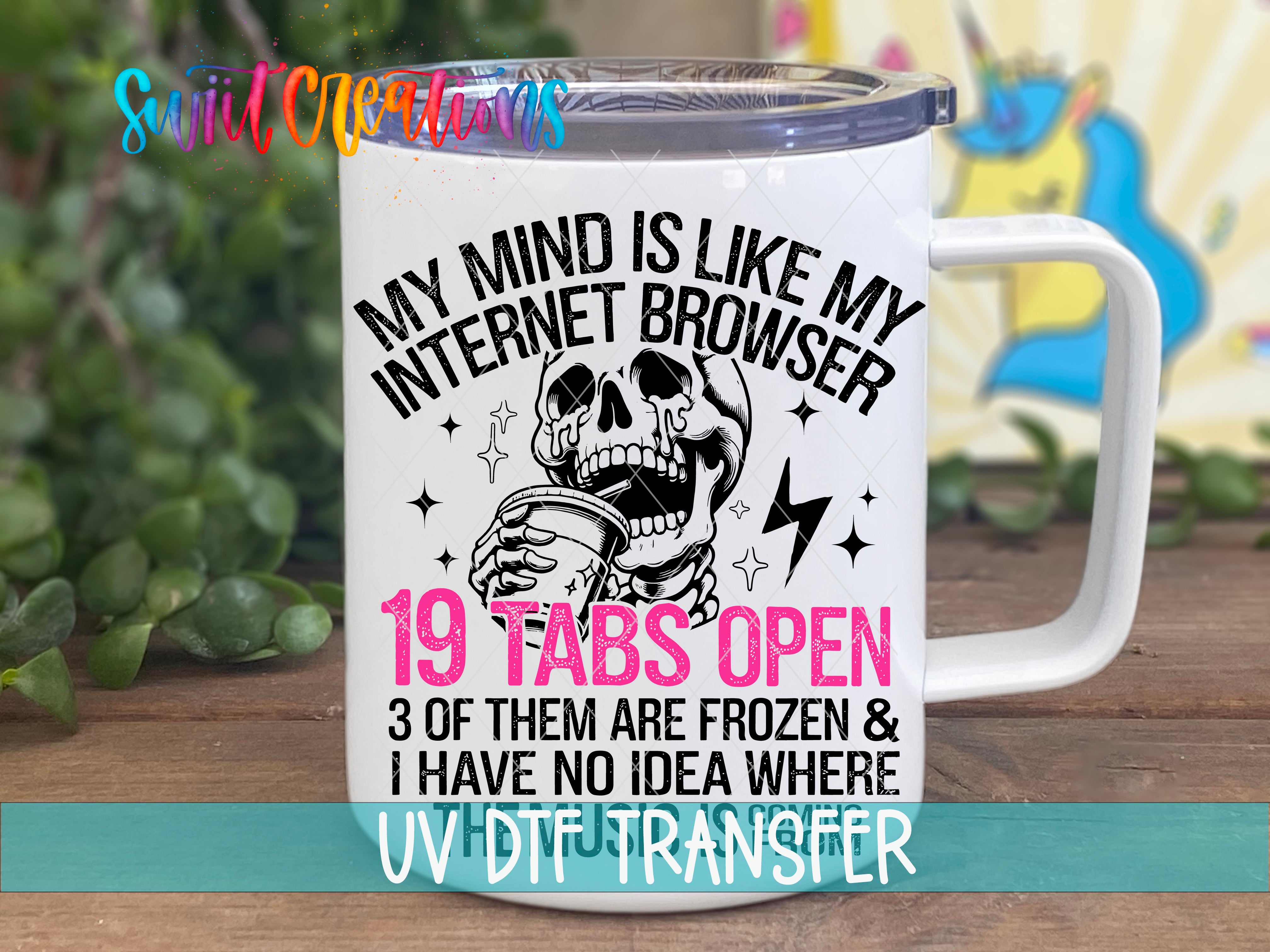 A white mug with a humorous text and graphic design printed on it, placed on a wooden surface.