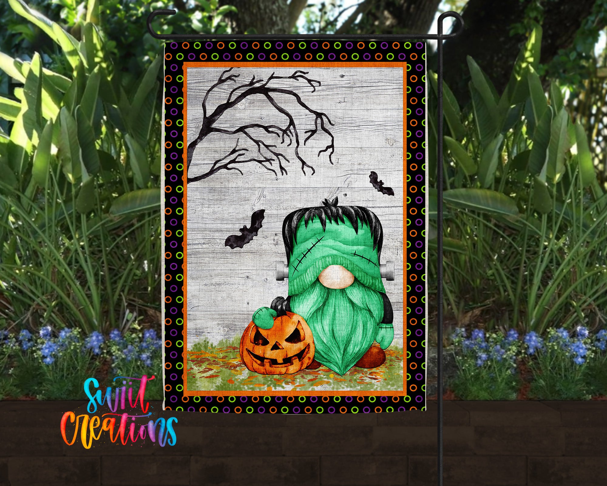 A Halloween-themed garden flag featuring a green gnome holding a carved pumpkin, with a spooky tree and bats in the background.