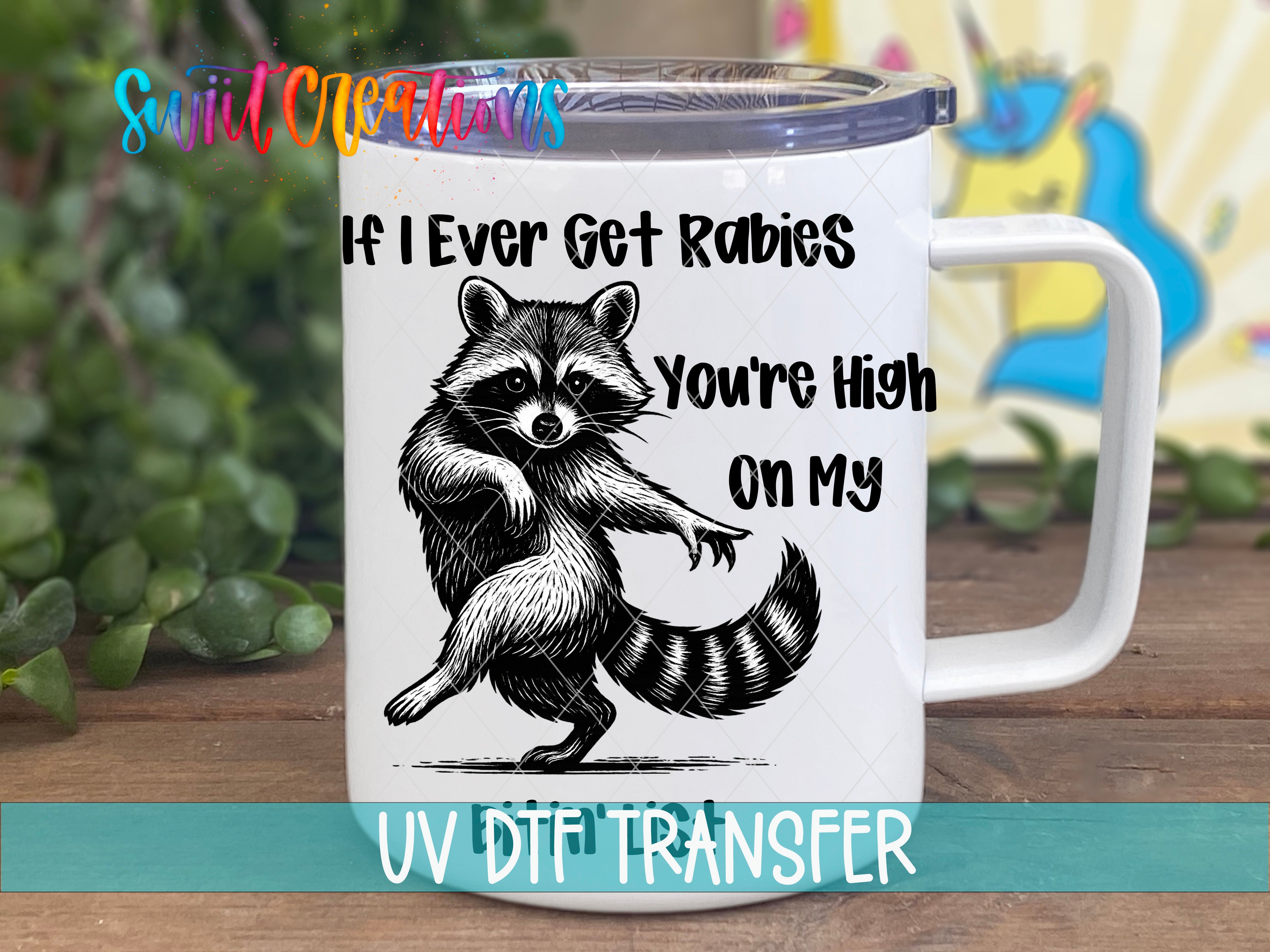 A mug with a raccoon graphic and text on it, placed on a wooden surface.