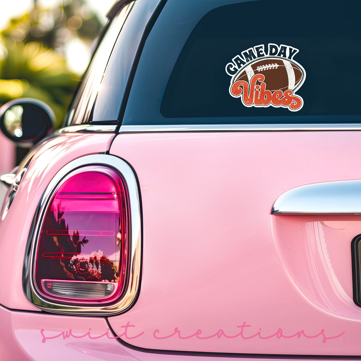 Football Game Day Vibes sticker on the back window of a pink car