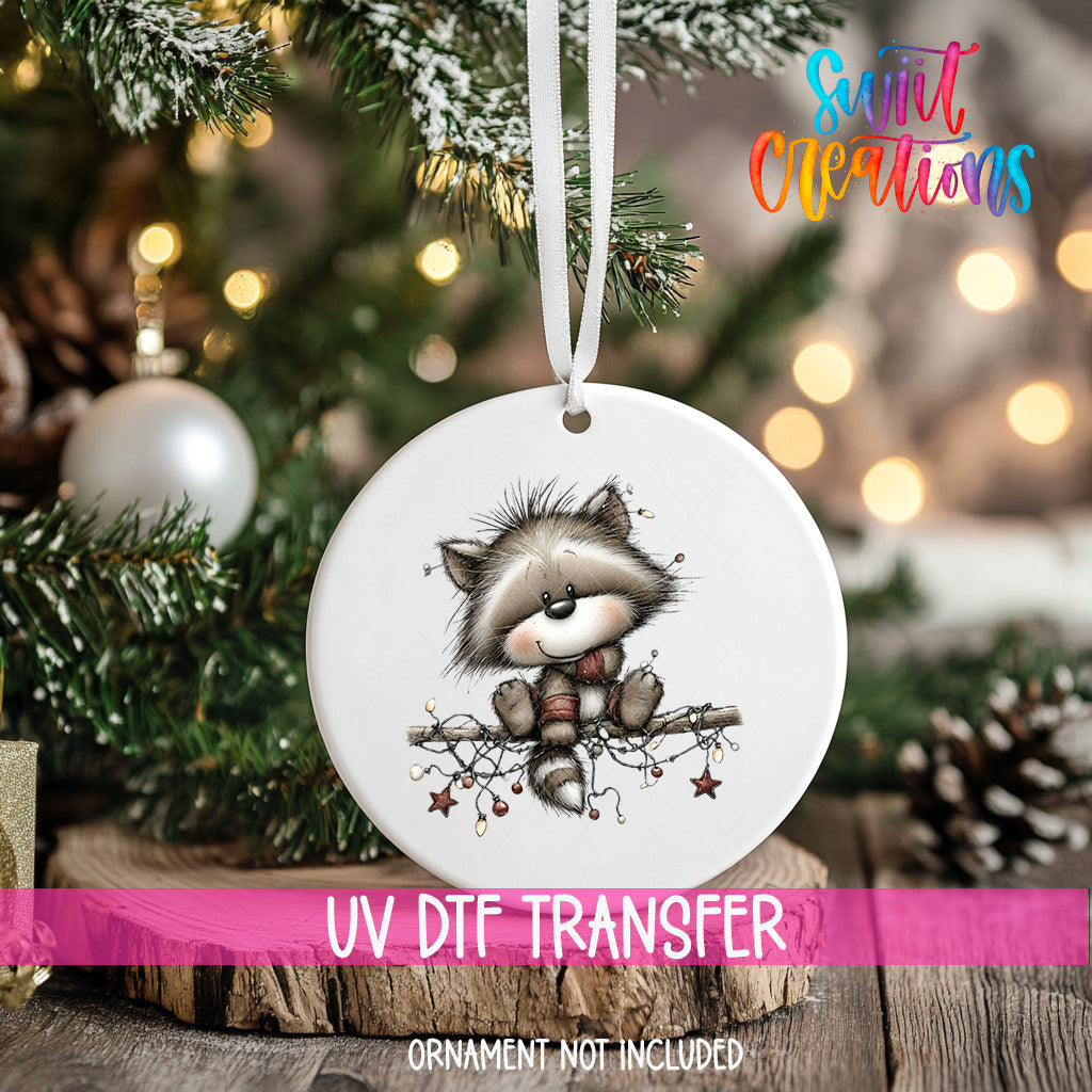 A white ceramic ornament with a raccoon sitting on a branch and holding a star, hanging on a Christmas tree.