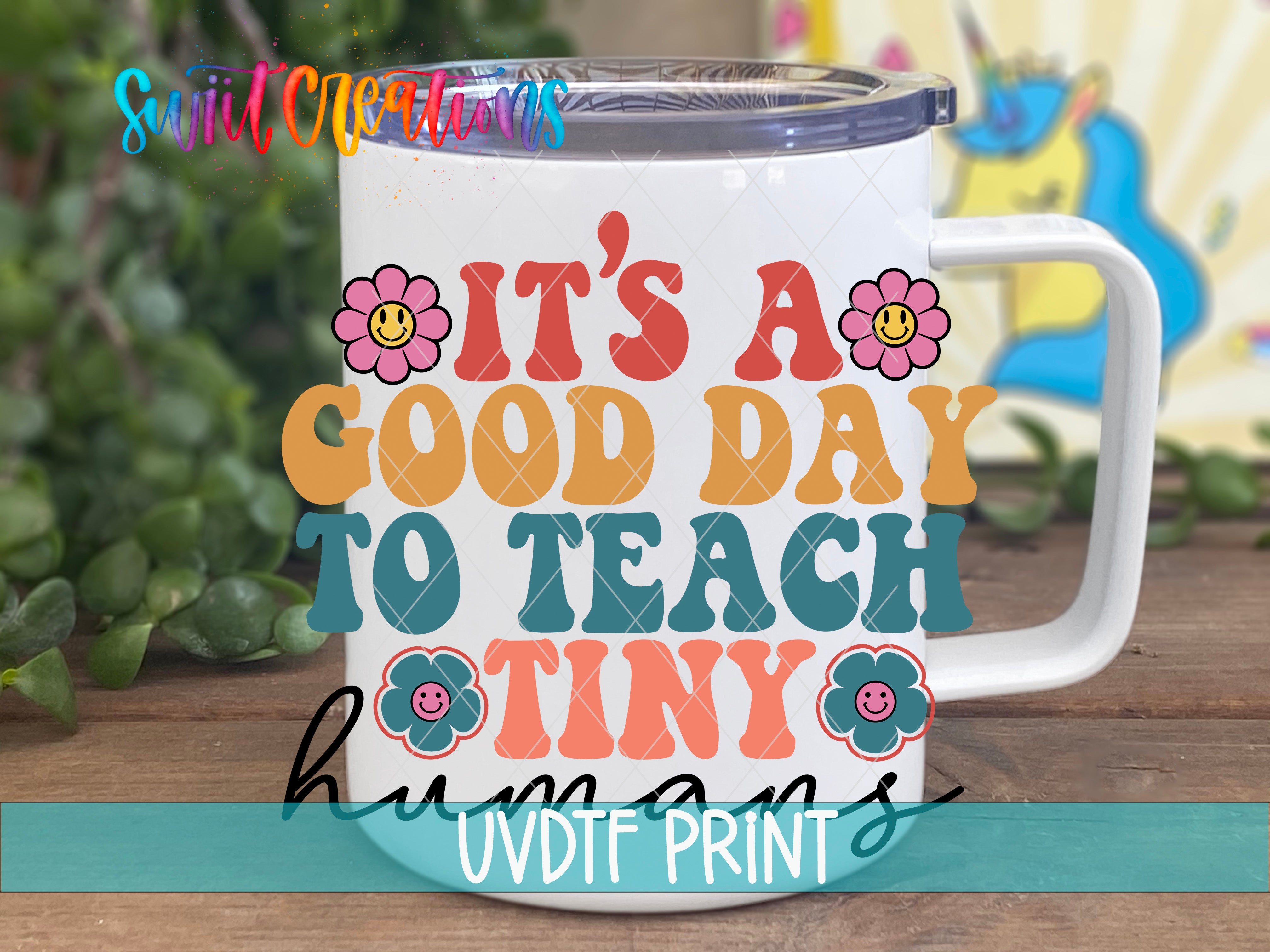A white mug with colorful text and flower-like graphics on it, placed on a wooden surface.