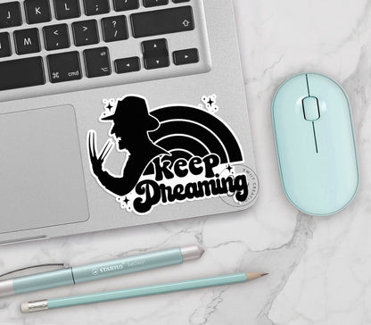 Keep Dreaming vinyl sticker on a silver laptop next to a mint mouse and pens