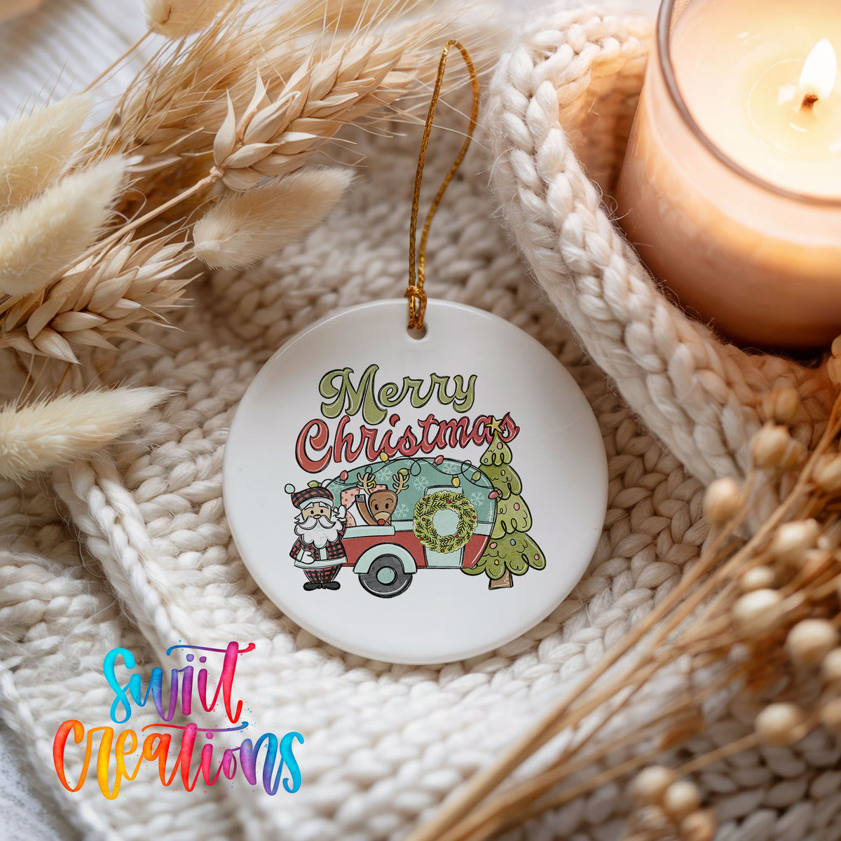 Merry Christmas Santa Camper ceramic Christmas ornament styled beside a candle and cozy knit blanket