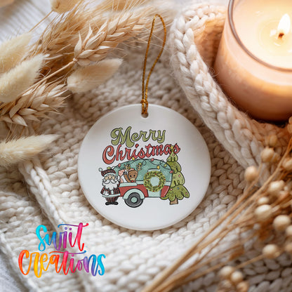 Merry Christmas Santa Camper ceramic Christmas ornament styled beside a candle and cozy knit blanket