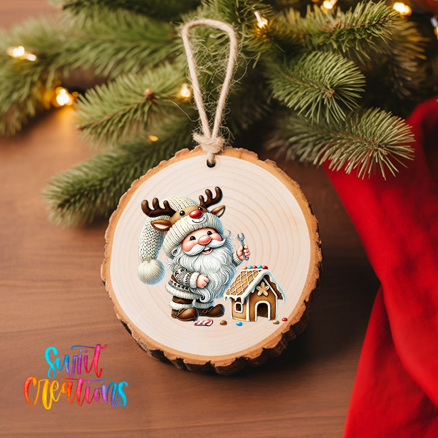 A wooden ornament featuring a smiling Santa Claus holding a wrench and standing next to a gingerbread house, with a Christmas tree in the background.