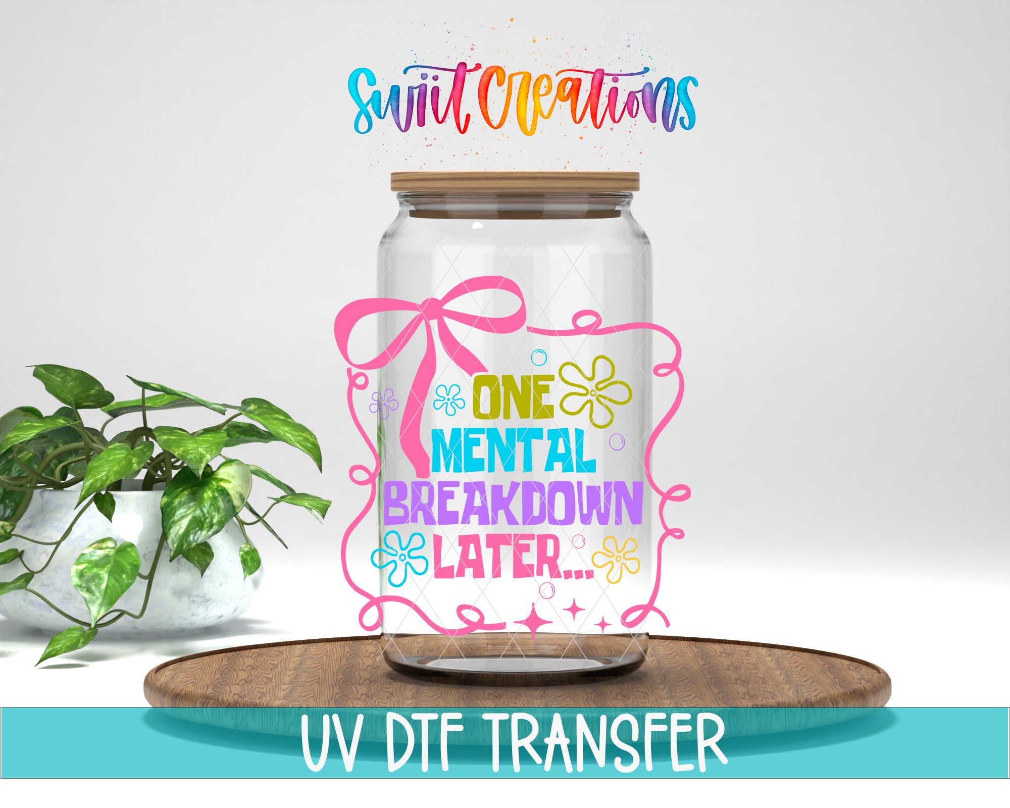 a glass jar with a colorful design and text, placed on a wooden surface next to a potted plant.