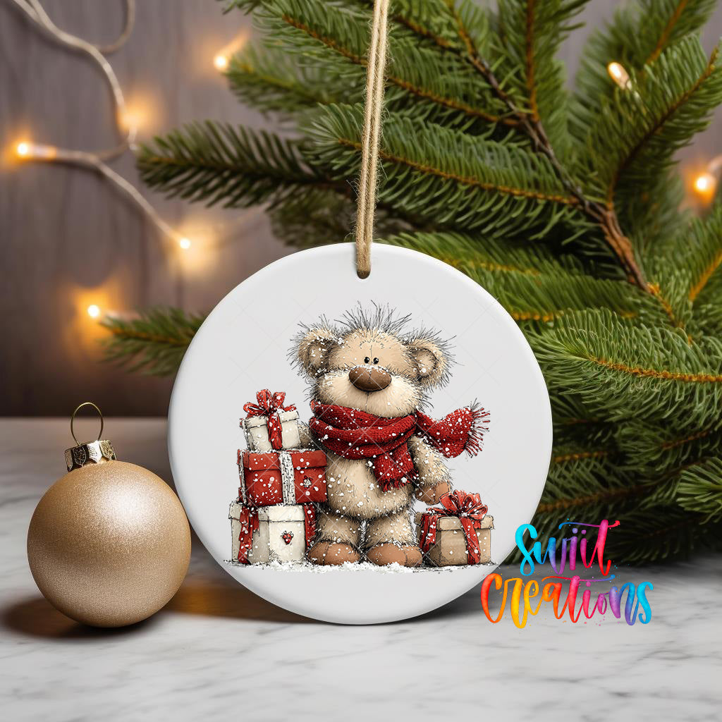 A white ceramic ornament featuring a teddy bear holding presents, surrounded by Christmas lights and a pine tree.