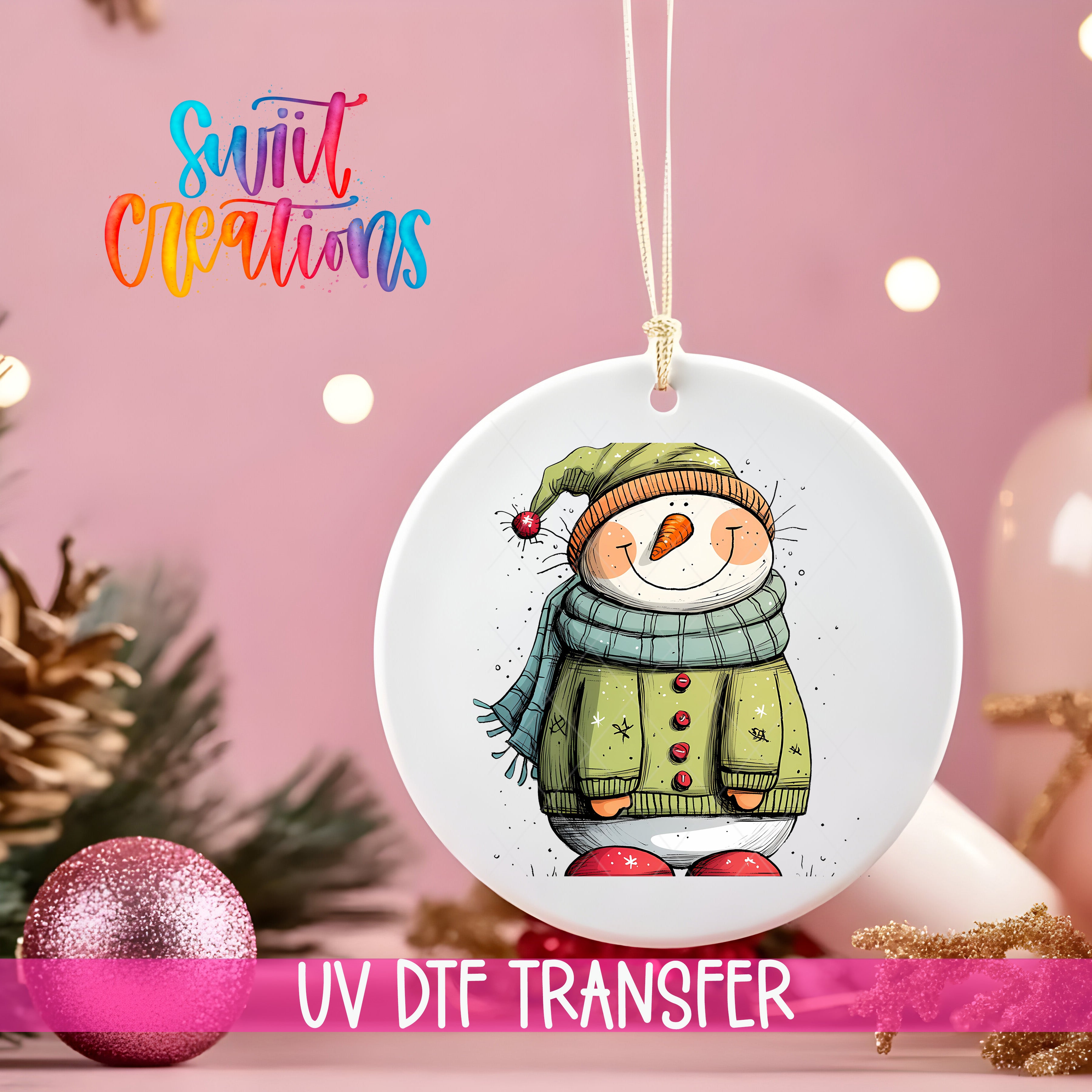 A white ornament with a snowman design hangs against a pink background, with a pink glitter ball and Christmas tree decorations visible in the background.