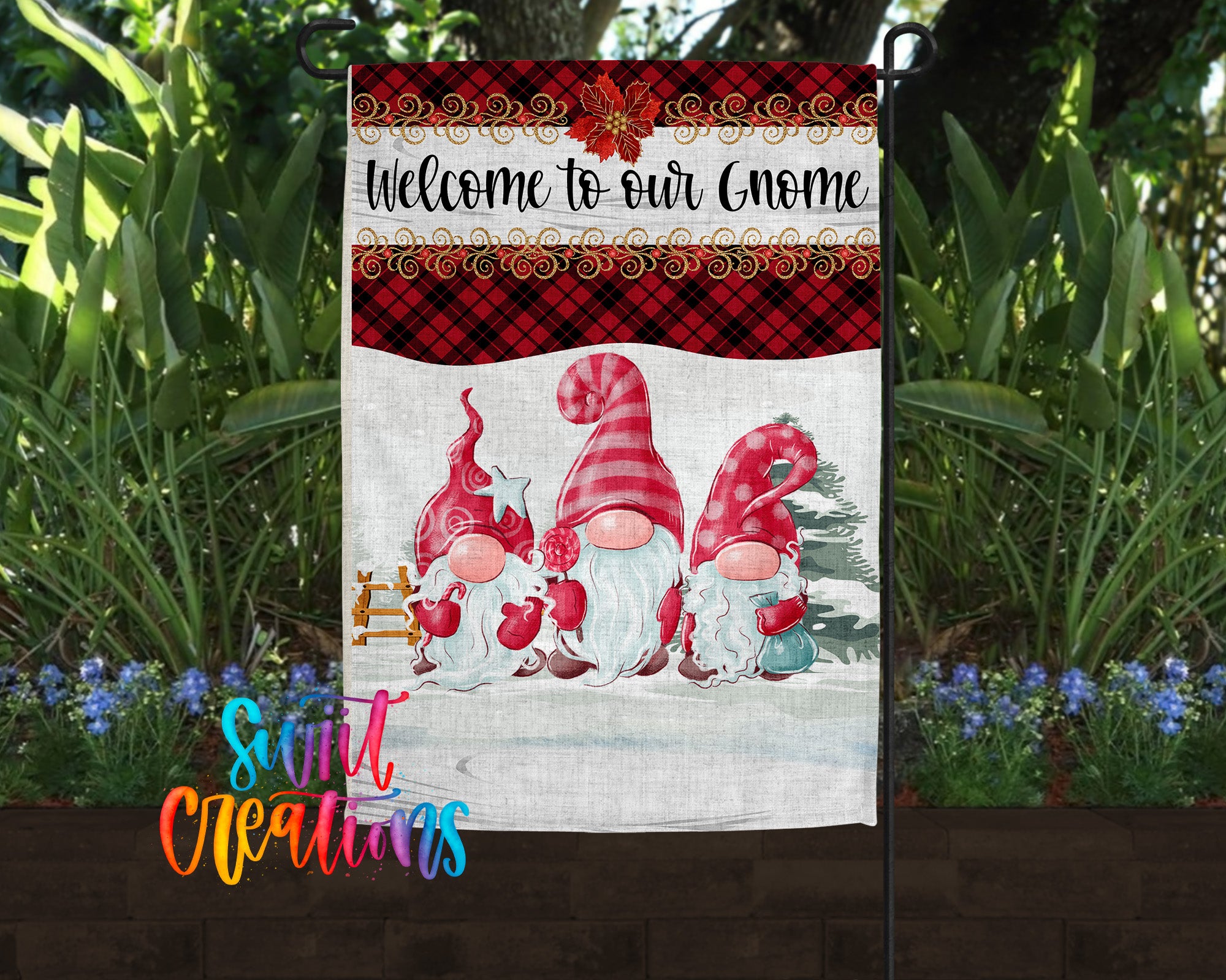 A garden flag featuring three gnomes in a snowy landscape, with a red and black plaid border and a "Welcome to our Gnome" message.