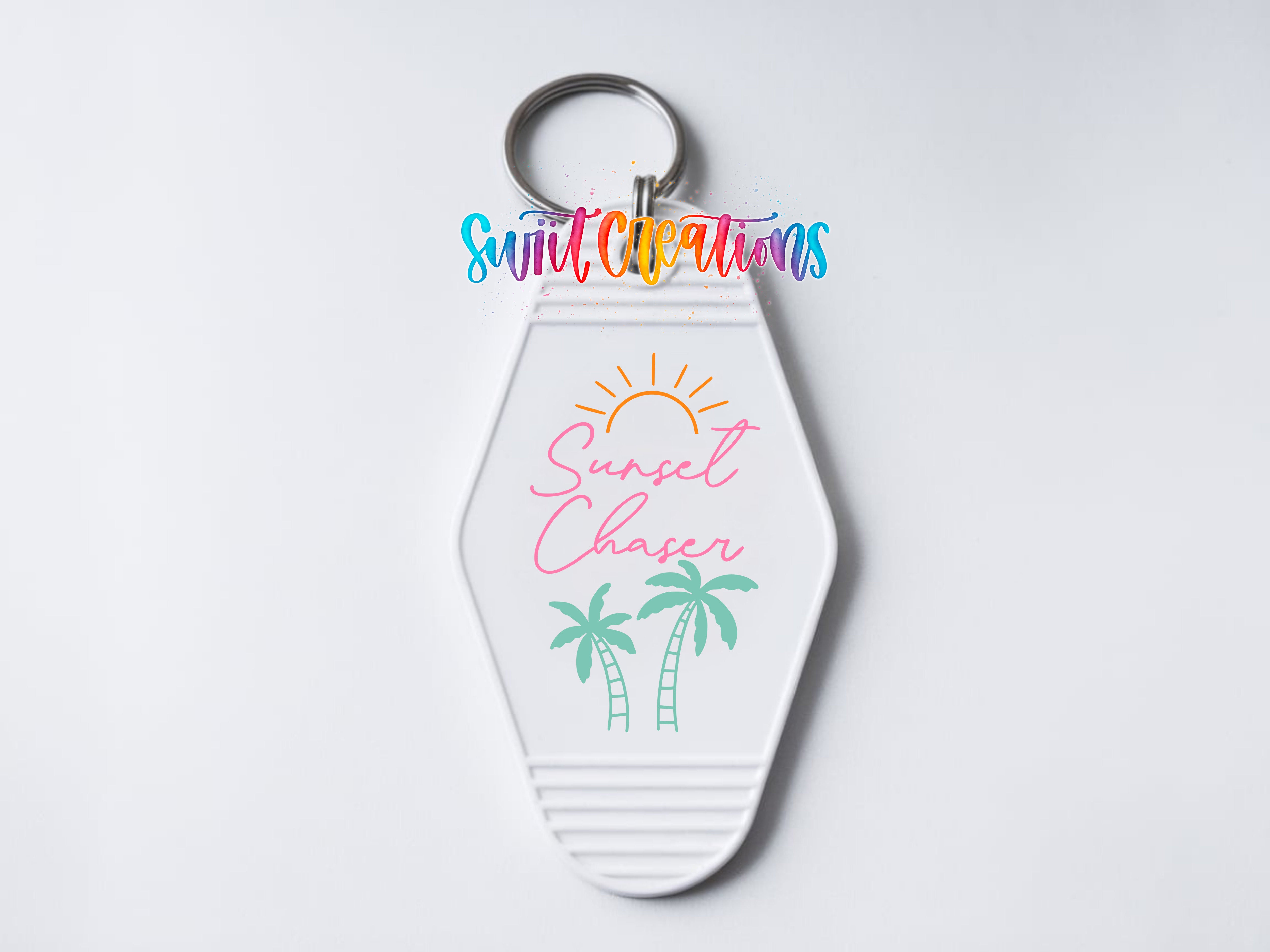 A keychain with a design featuring a sun and palm trees, along with the text "Sunset Chaser" written on it.