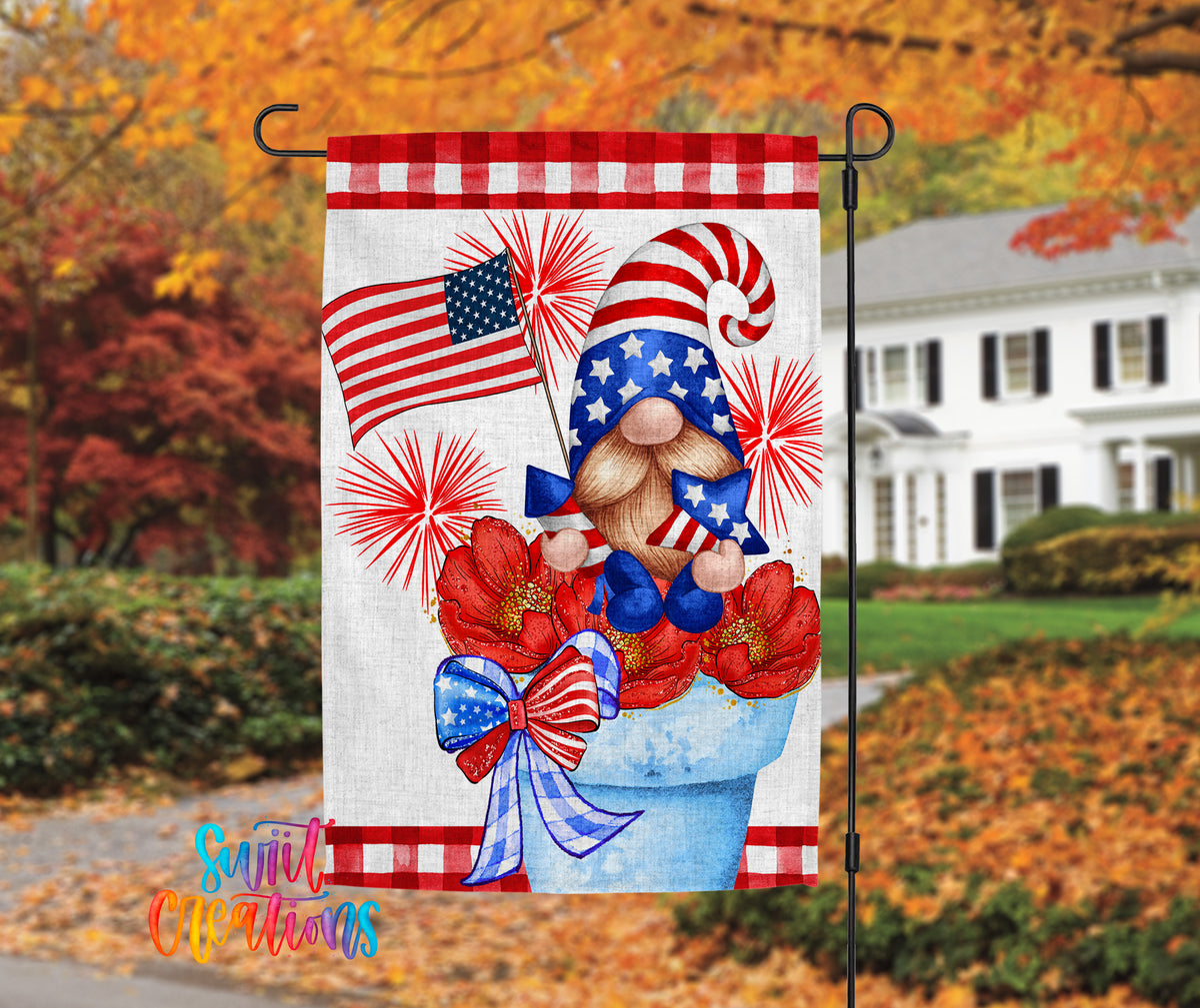 A patriotic flag featuring a gnome holding a flag and flowers, with a house and autumn foliage in the background.