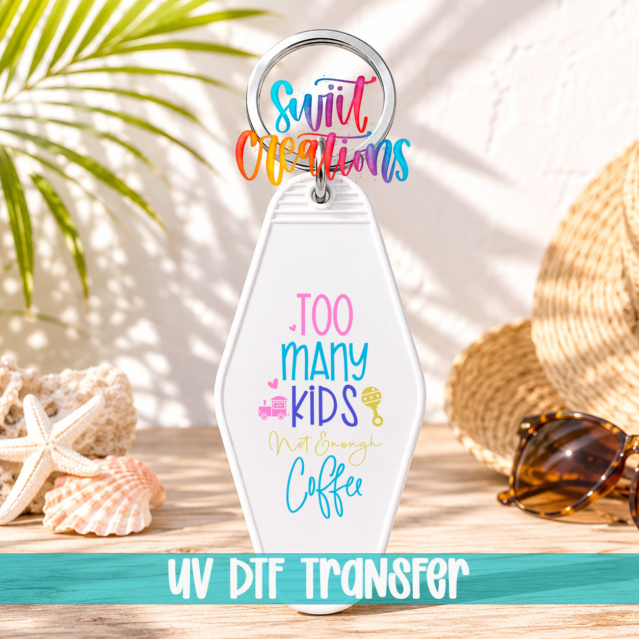 A keychain with a colorful design and text, placed on a wooden surface with sunglasses and a straw hat in the background.