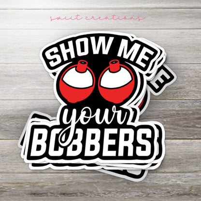Stack of Show Me Your Bobbers glossy stickers on a gray wood table