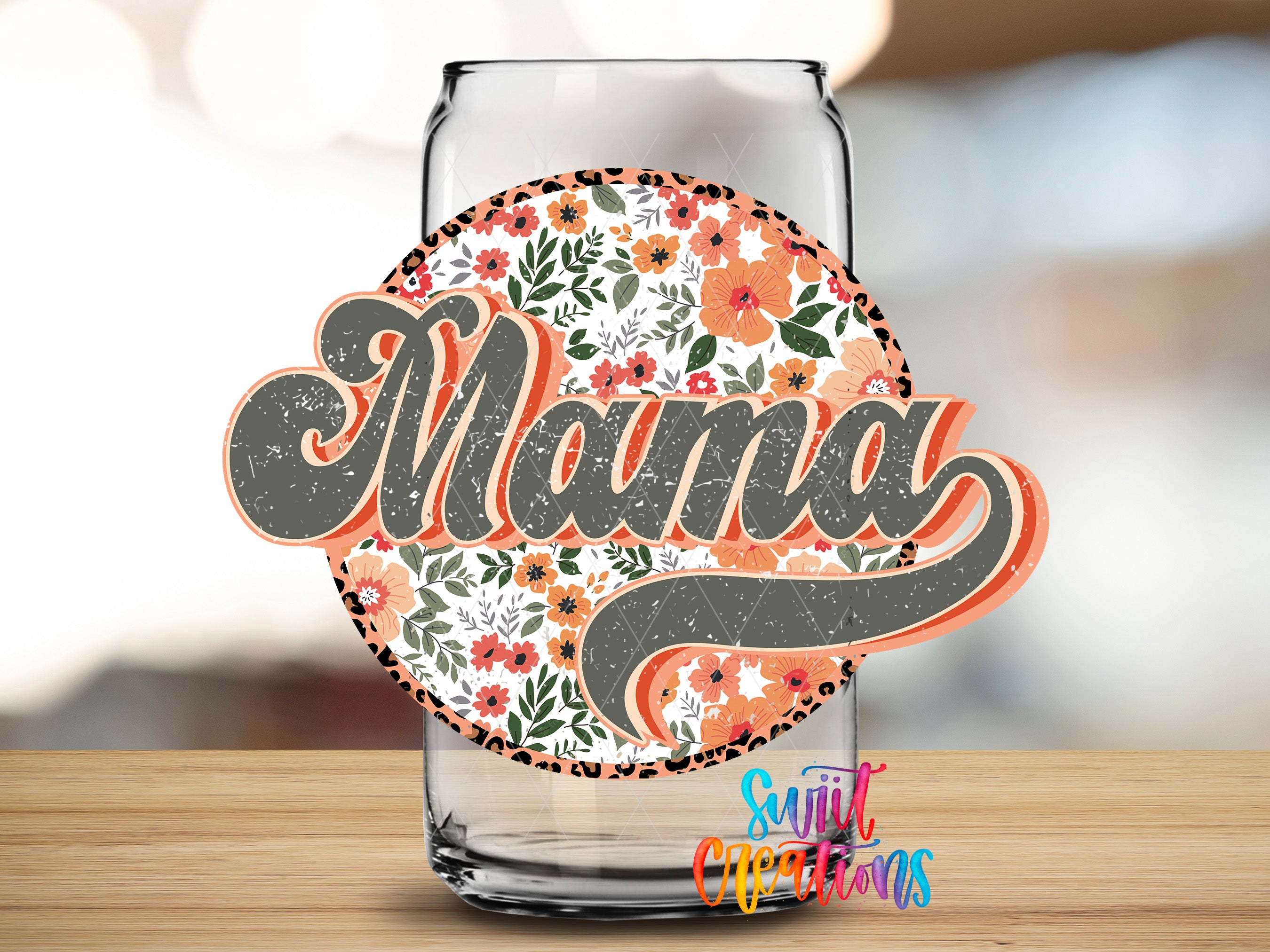 A glass can with a floral design and the word "Mama" written on it, placed on a wooden surface.