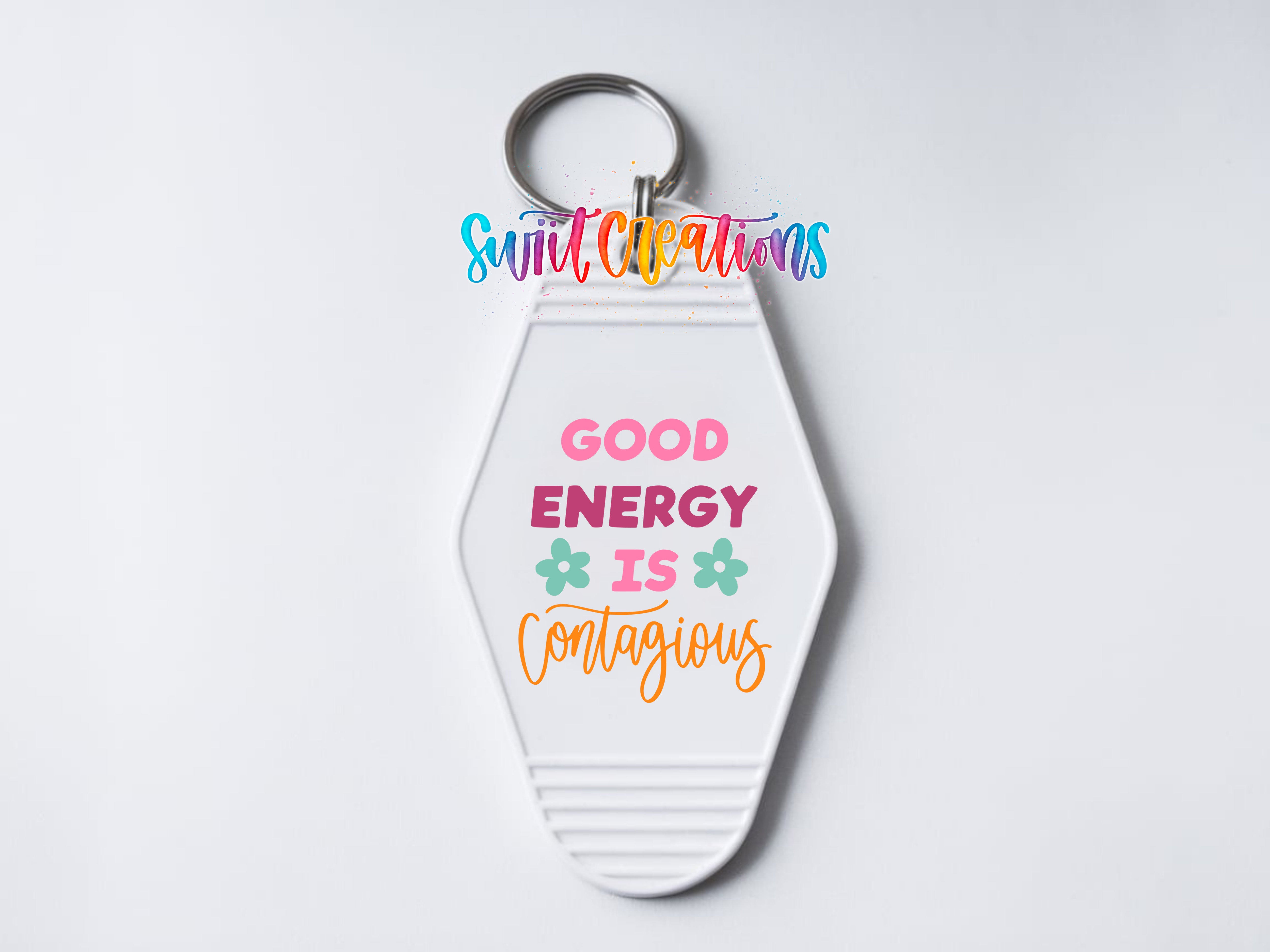 A keychain with a message that says "GOOD ENERGY IS CONTAGIOUS" in a colorful, stylized font.