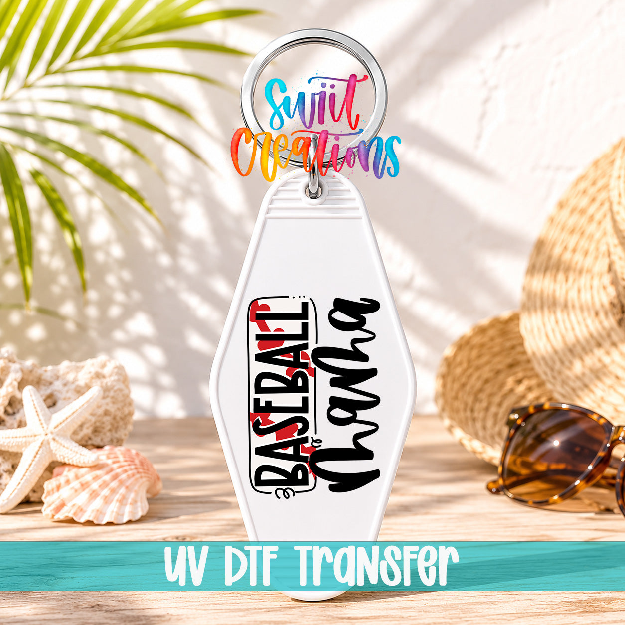 A keychain with the text "Baseball Wana" printed on it, along with a colorful ring and a straw hat, all placed on a wooden surface with a palm tree and sunglasses in the background.