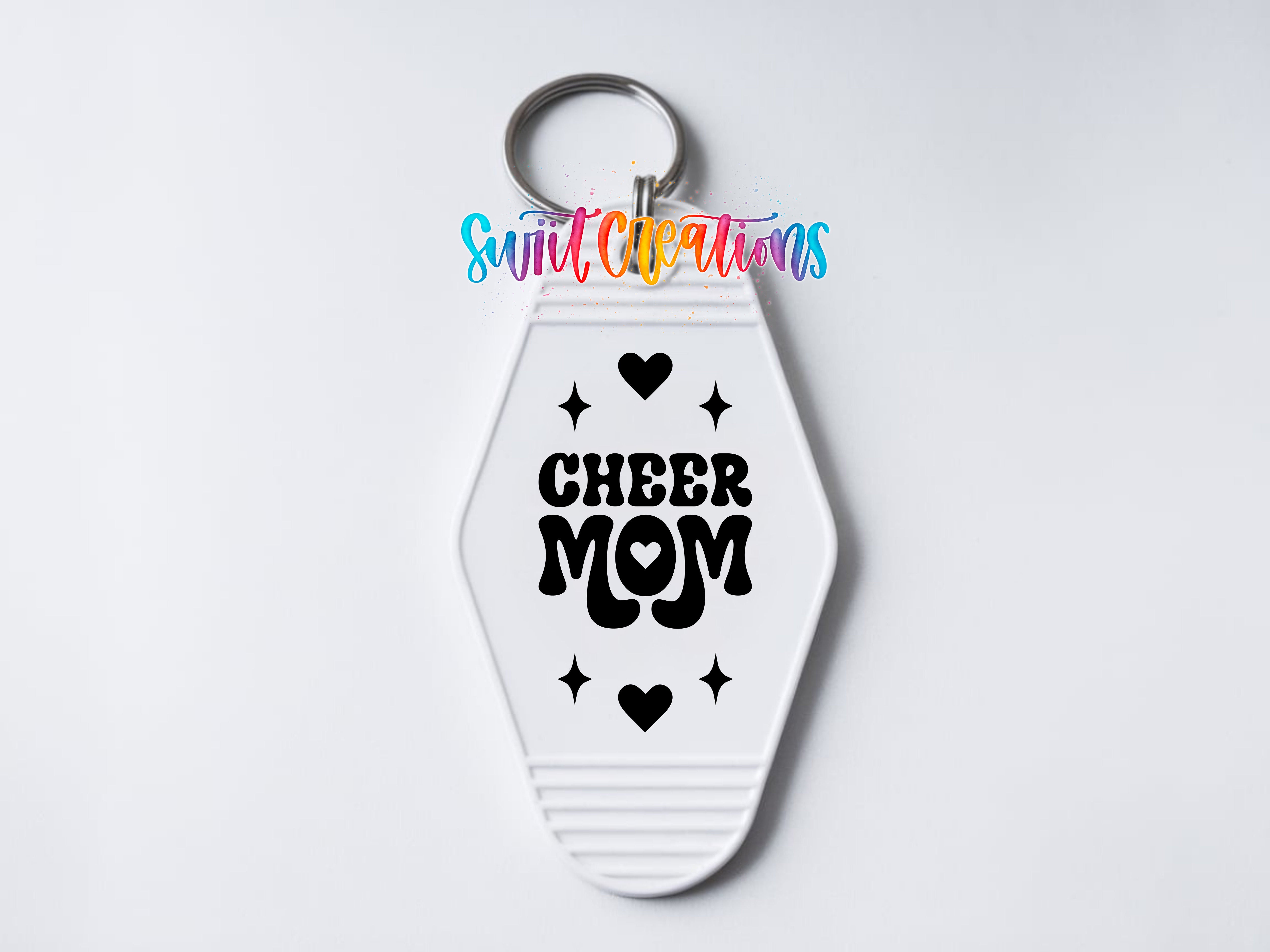 A keychain with a white hexagon shape and the text "CHEER MOM" printed on it.