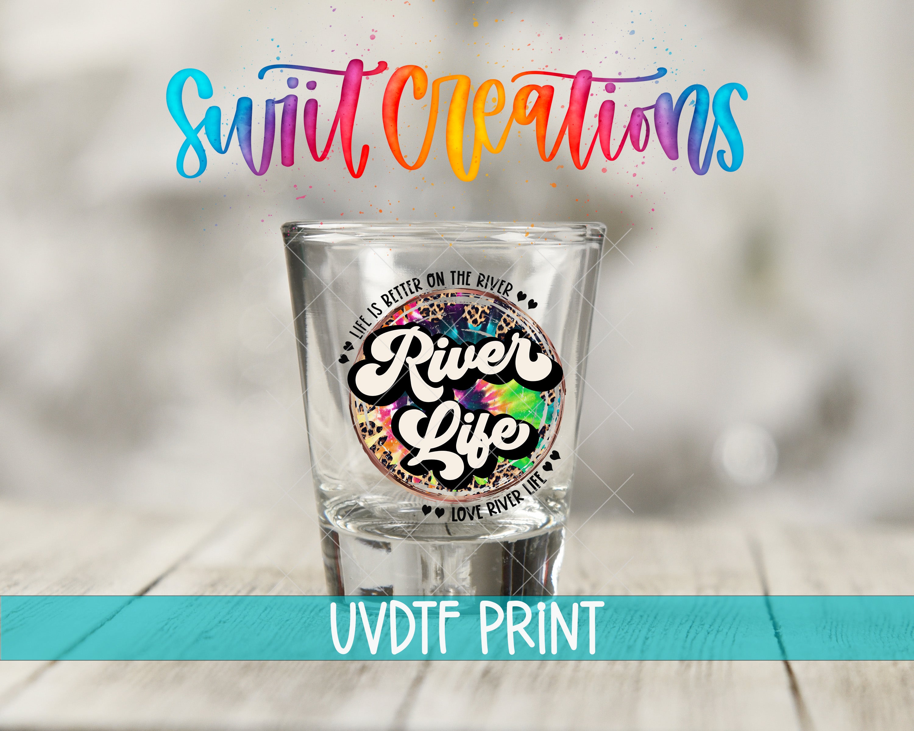 a shot glass with a colorful, tie-dye design and text printed on it, placed on a wooden surface.
