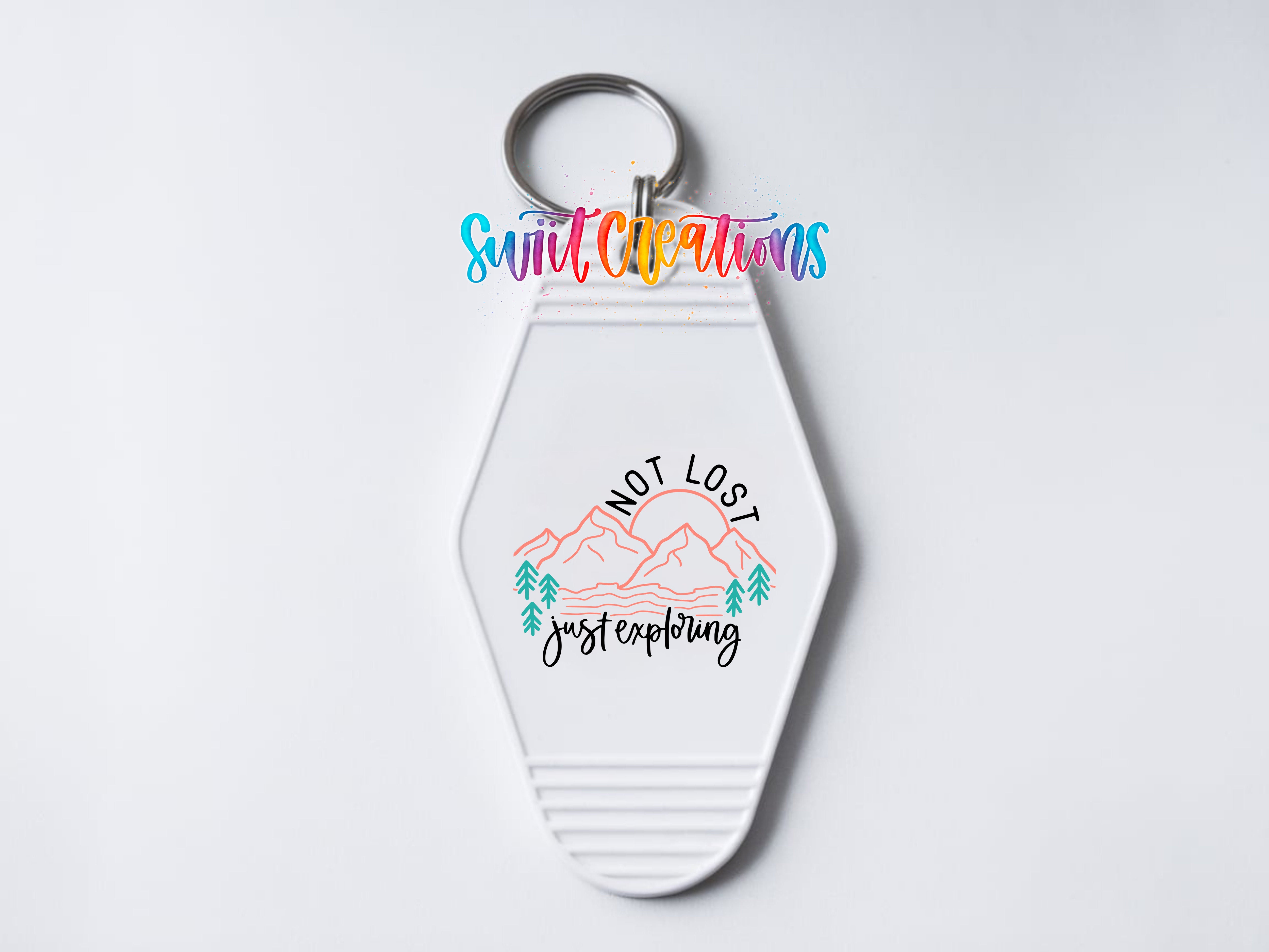 A keychain with a design featuring mountains and trees, along with the text "NOT LOST just exploring".