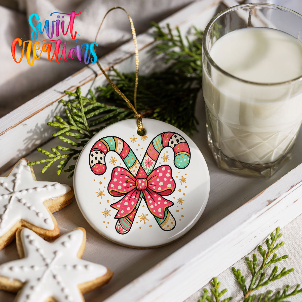 a festive arrangement with a candy cane ornament, cookies, and a glass of milk on a white tray.