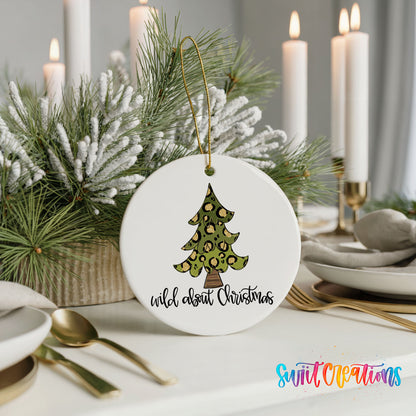 A white Christmas ornament with a leopard print tree design, placed on a table with candles and a floral arrangement.