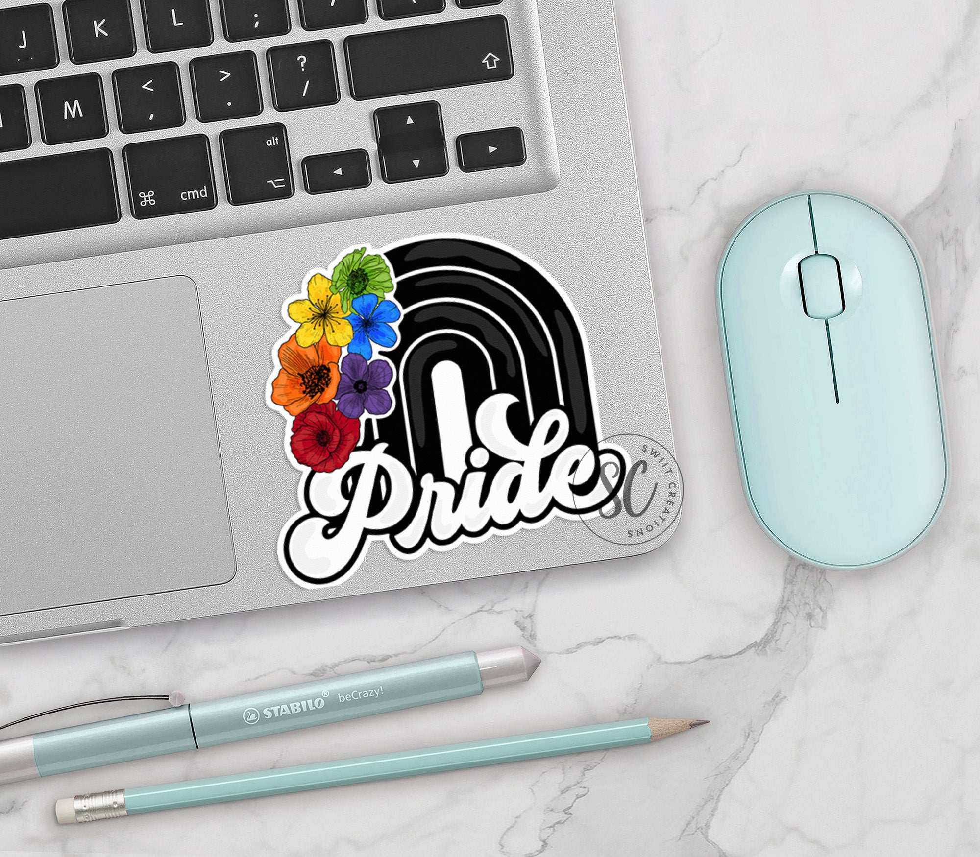 a laptop with a sticker of the word pride on it next to a mouse