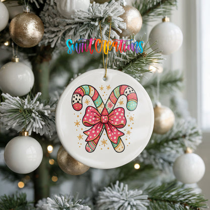 A white ceramic ornament with a colorful candy cane design hangs from a Christmas tree, surrounded by white and gold ornaments.
