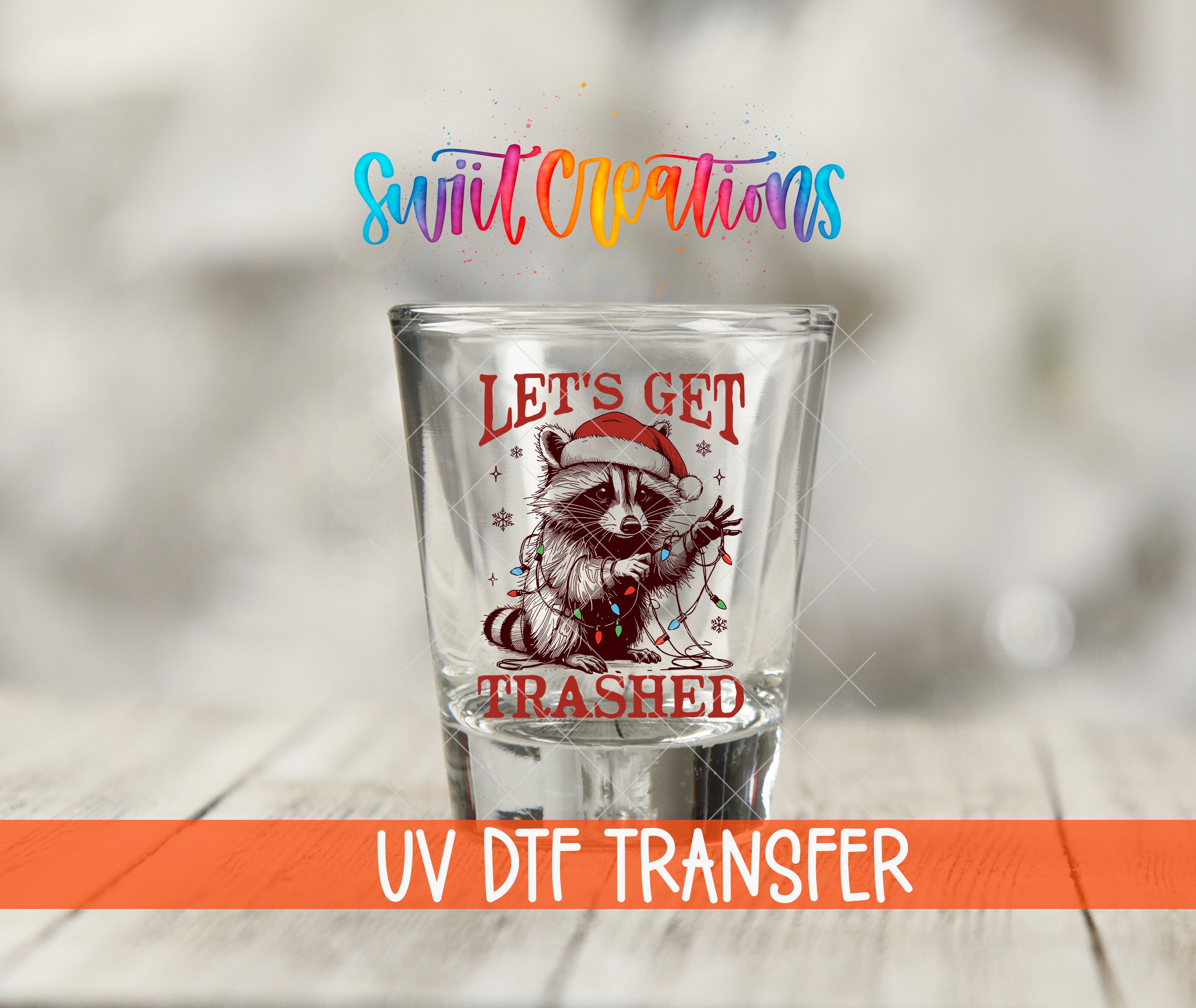 A shot glass with a raccoon wearing a Santa hat and the text "Let's get trampled" printed on it, along with a colorful logo and text that says "Swift Creations UV Dtf Transfer".