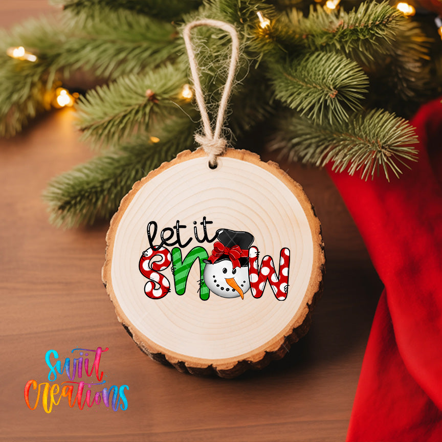 A wooden ornament with the text "let it snow" hanging from a tree branch, surrounded by Christmas lights and greenery.